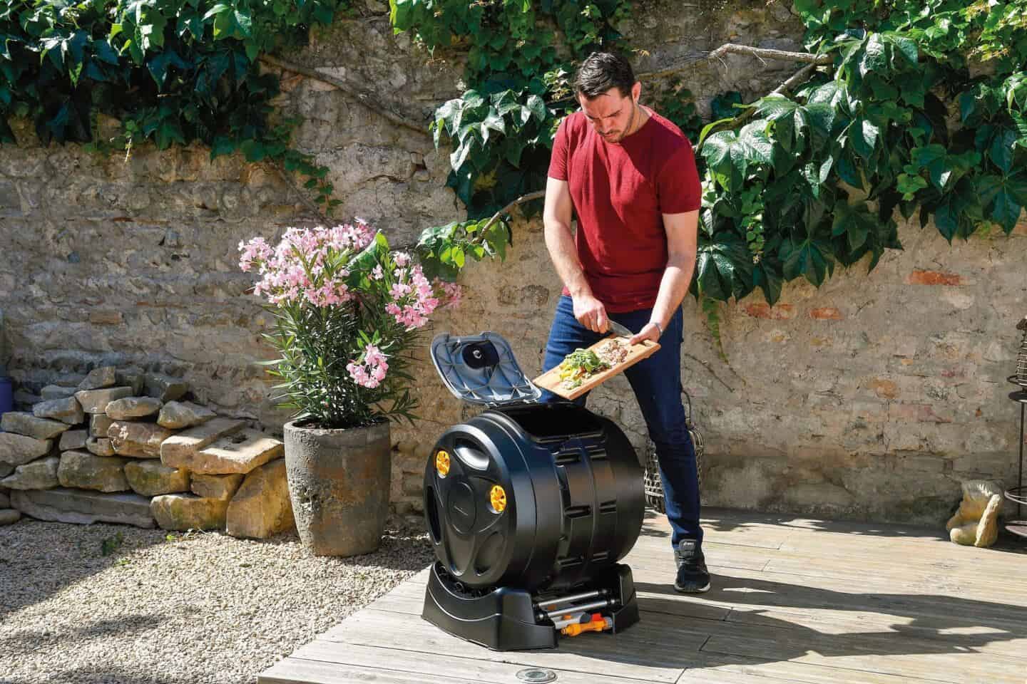 A man scrapes food scraps into a composter in the garden