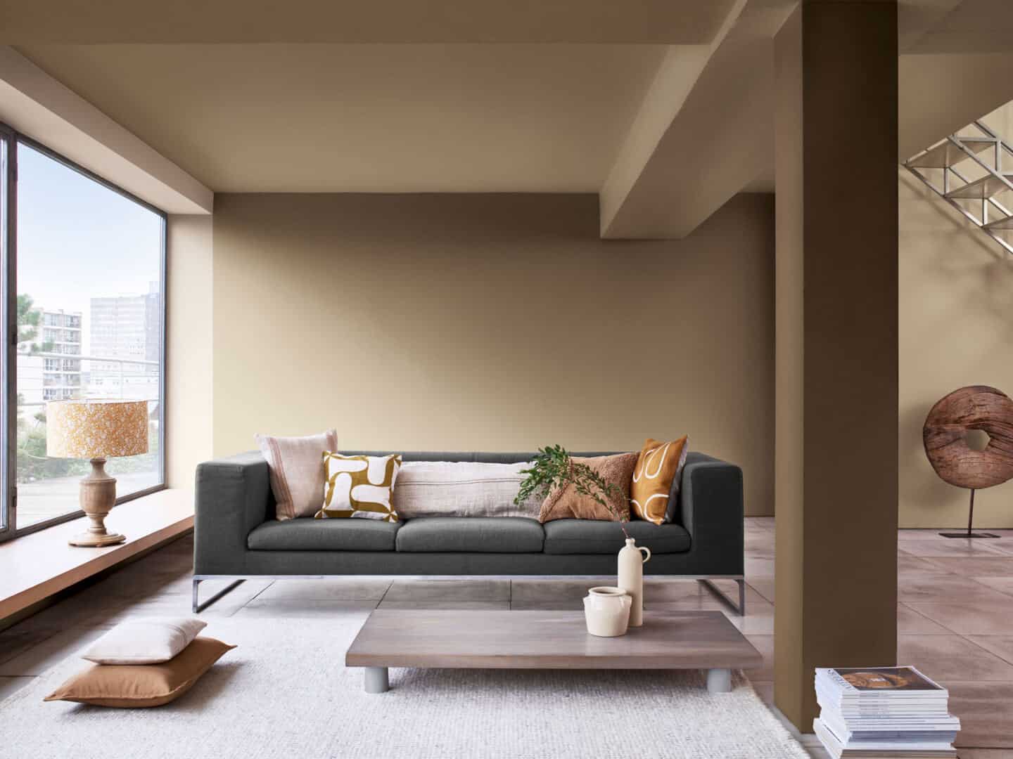 A brown living room with large window, green sofa and extremely low coffee table