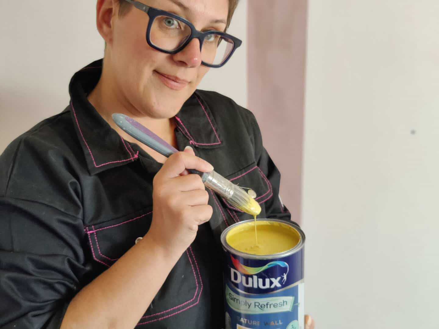 A woman dipping a paint brush into a paint pot