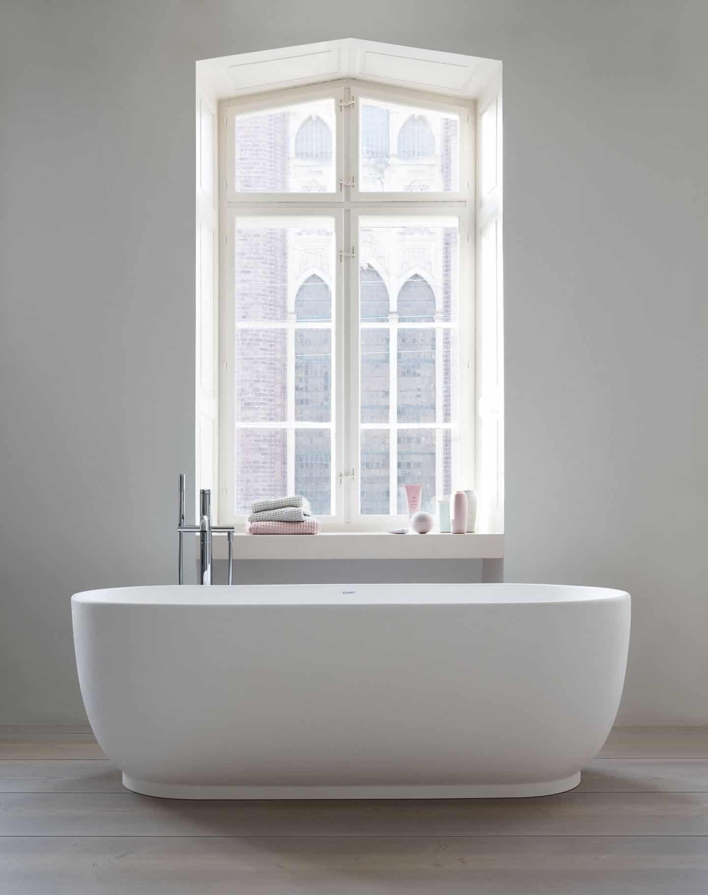 A freestanding bathtub infront of a large window. Bathtub from the Luv collection by luxury bathroom brand Duravit. 