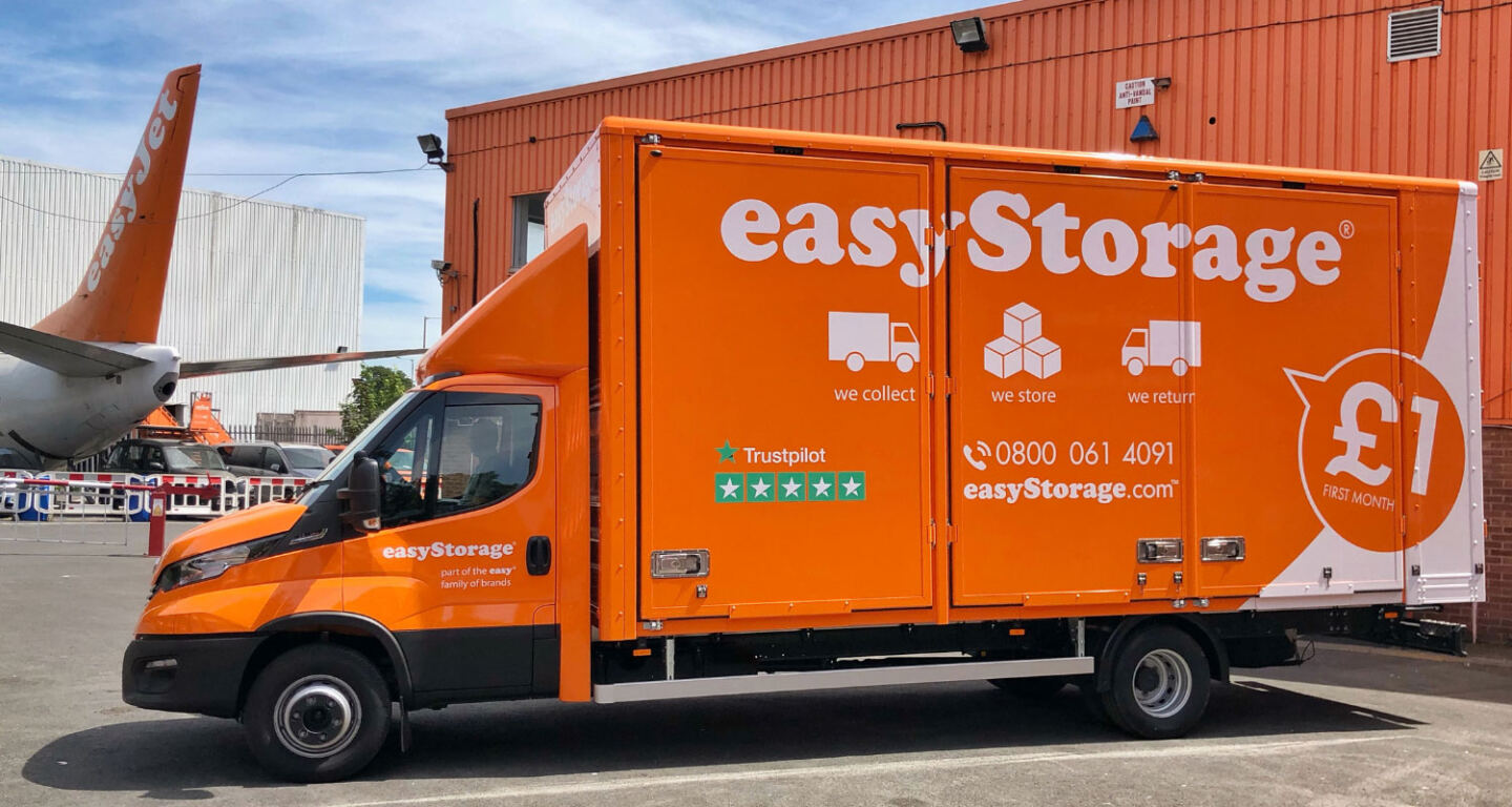 A big orange easyStorage van is parked outside a self-storage facility