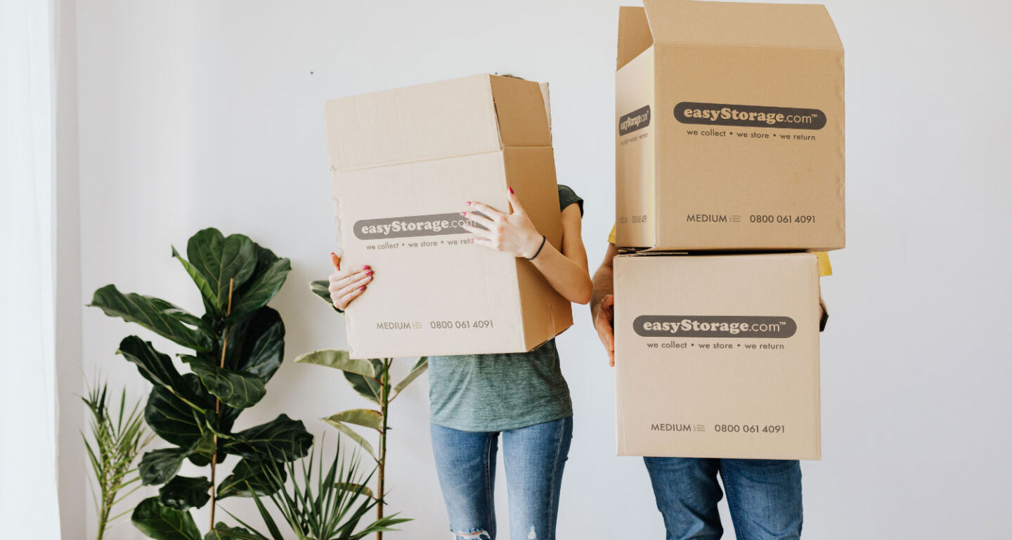 A man and a women carrying  cardboard boxes 