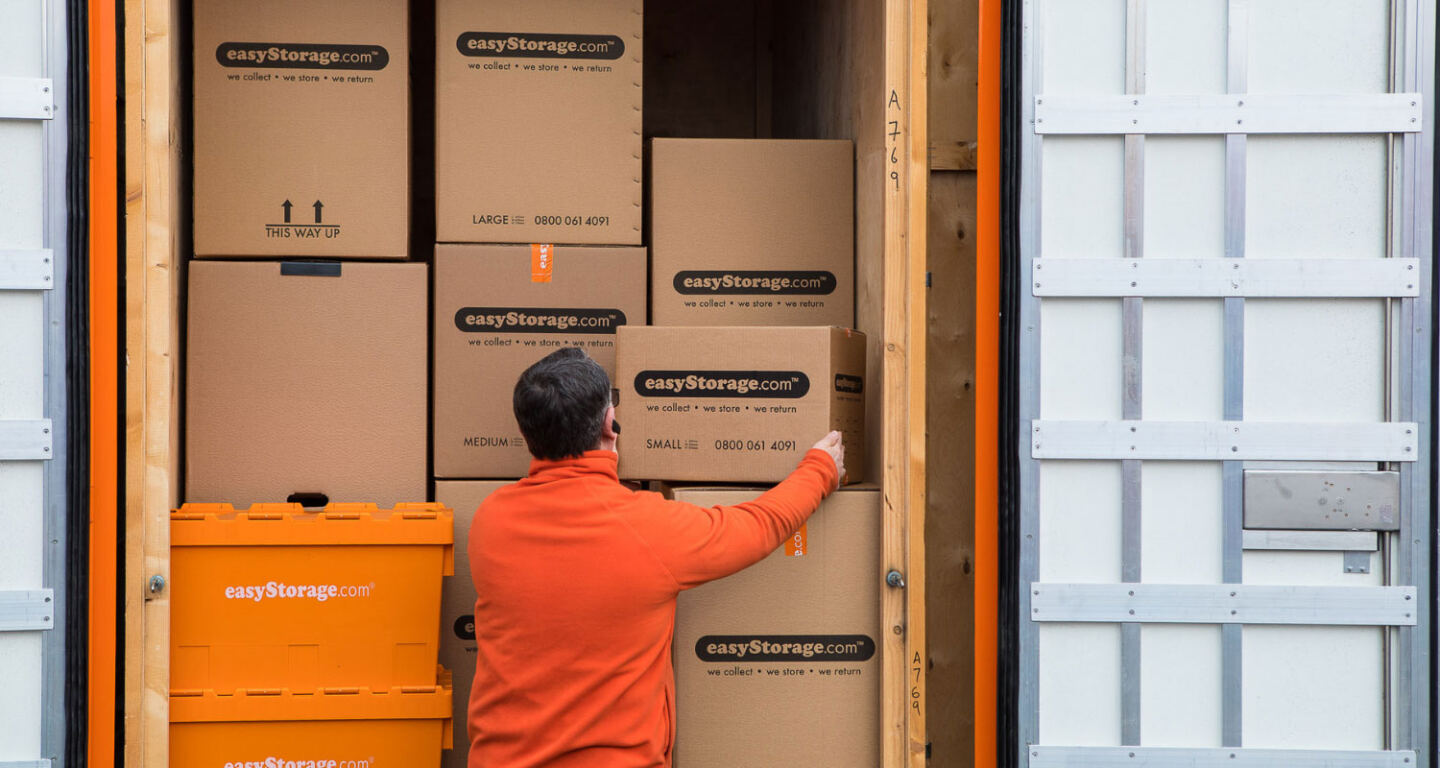 An easyStorage employee loads carboard boxes into the back of an easyStorage van ready to be taken away for self-storage