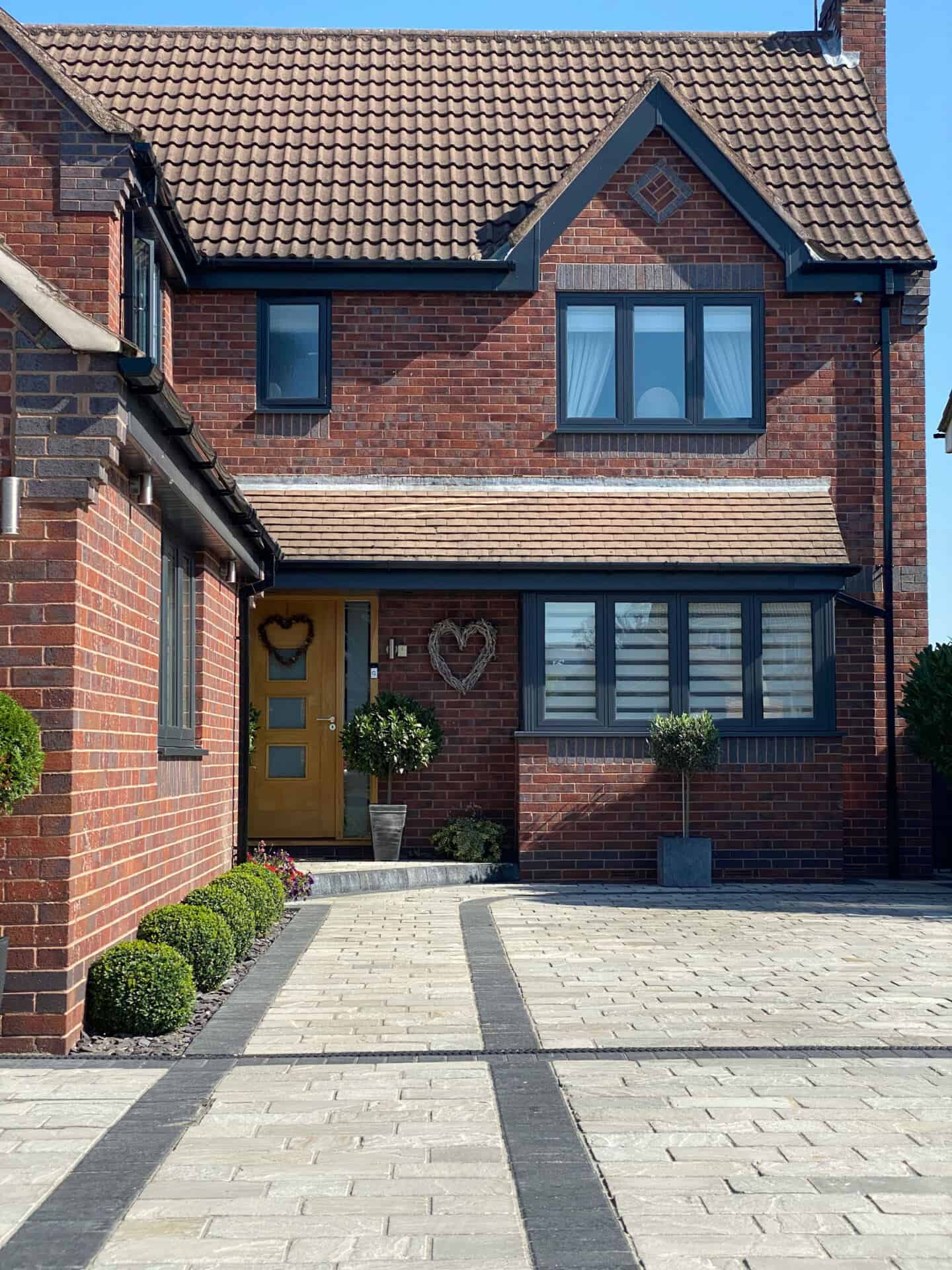 A detached red brick home with a driveway made from stone pavers