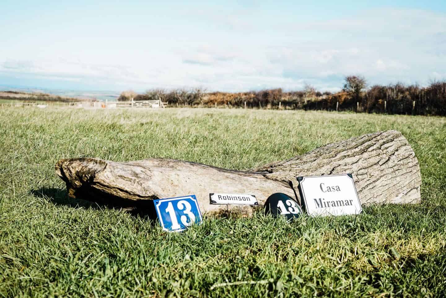 Enamel house signs against a log in a field