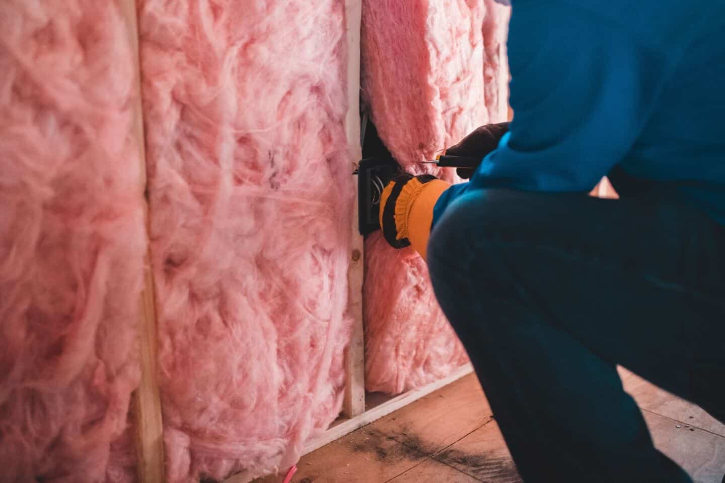 A man fitting pink wall insulation