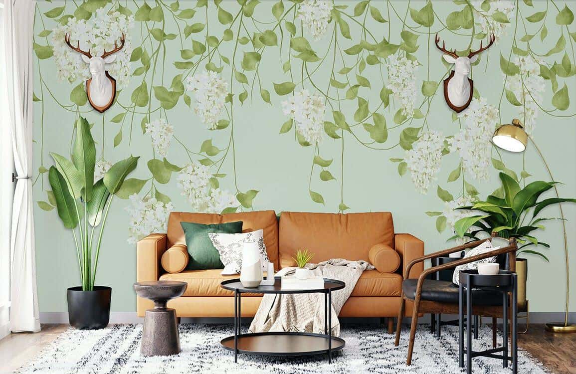 Ever Wallpaper mural of hanging vine leaves and white flowers behind a brown leather sofa and a round black metal coffee table