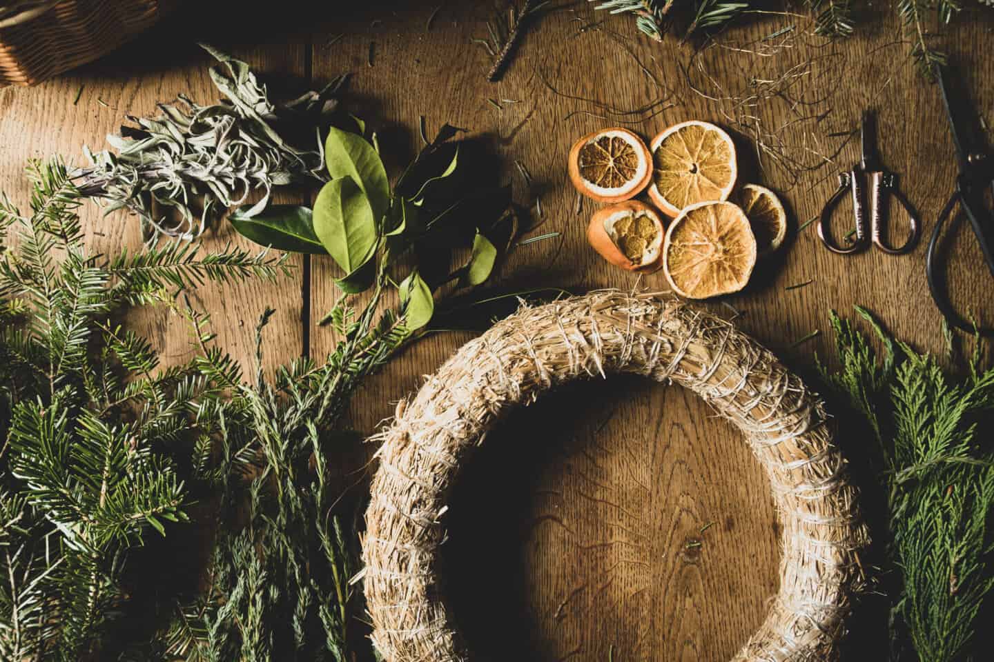 Materials for making a Christmas wreath spread across a wooden table