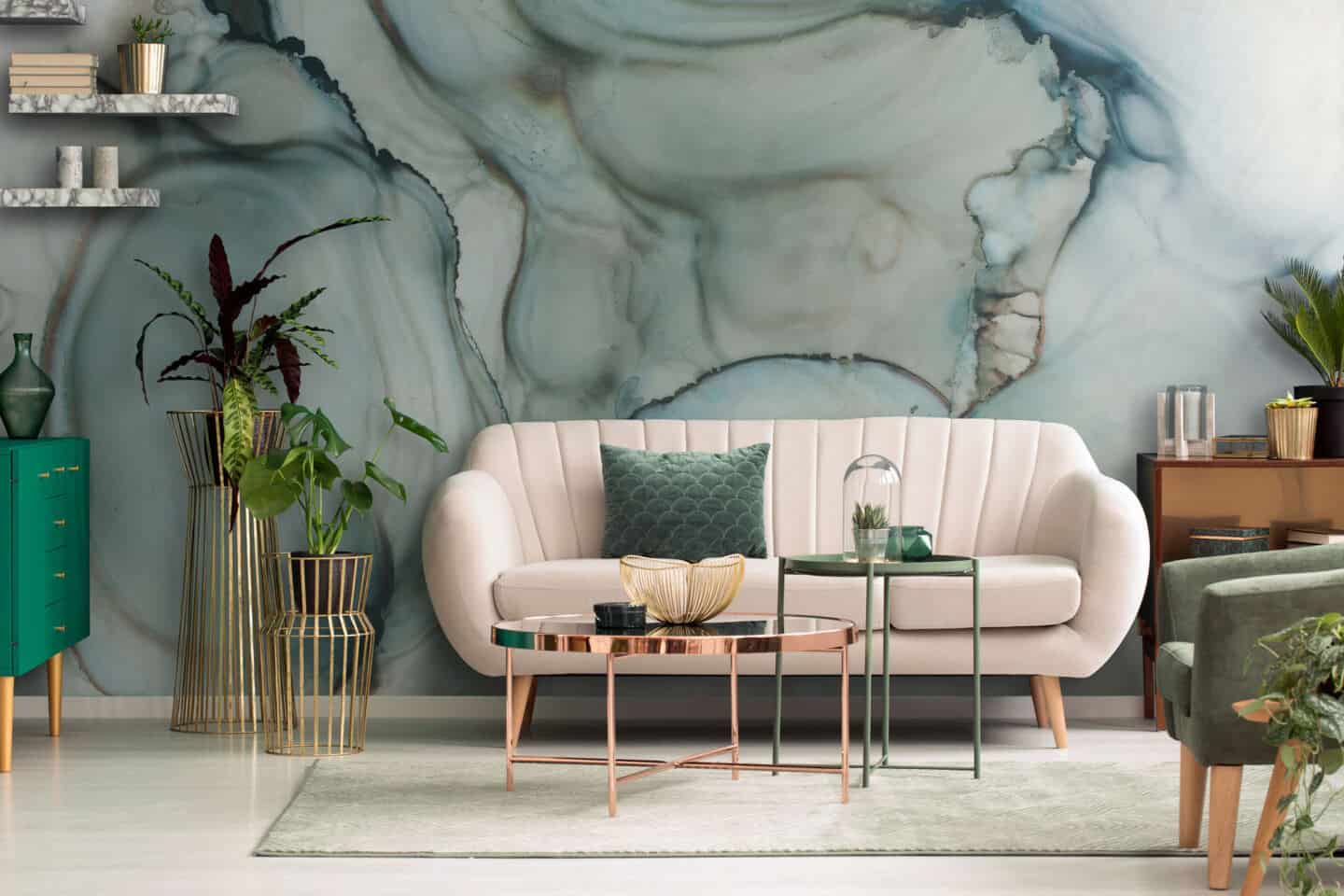 A white sofa on a neutral rug infront of a jade green abstract painted wall mural.