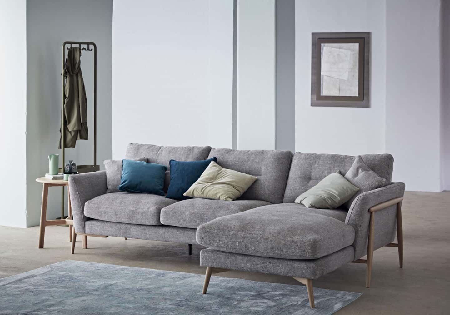 A grey chaise-style sofa on a blue rug in a living room