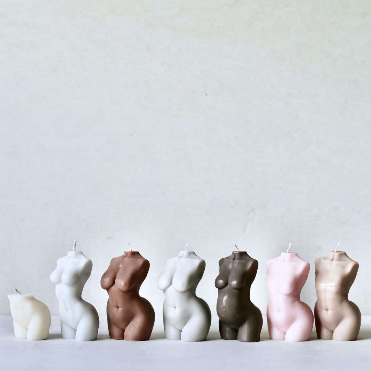 7 candles in various skin tones in the shape of the naked female torso