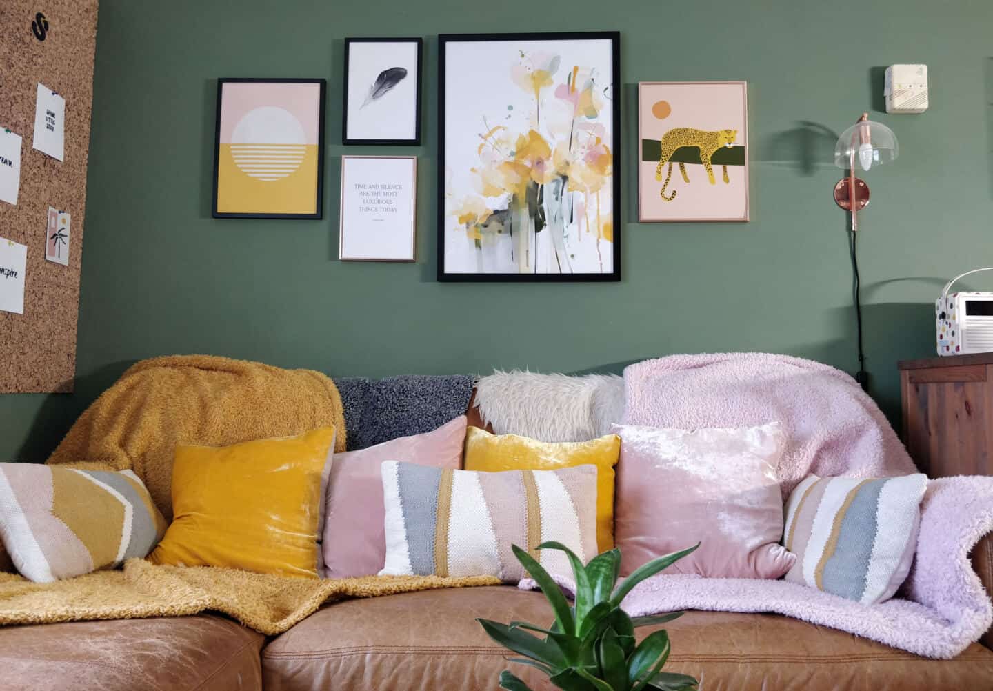 Artwork gallery wall hung above a brown leather sofa