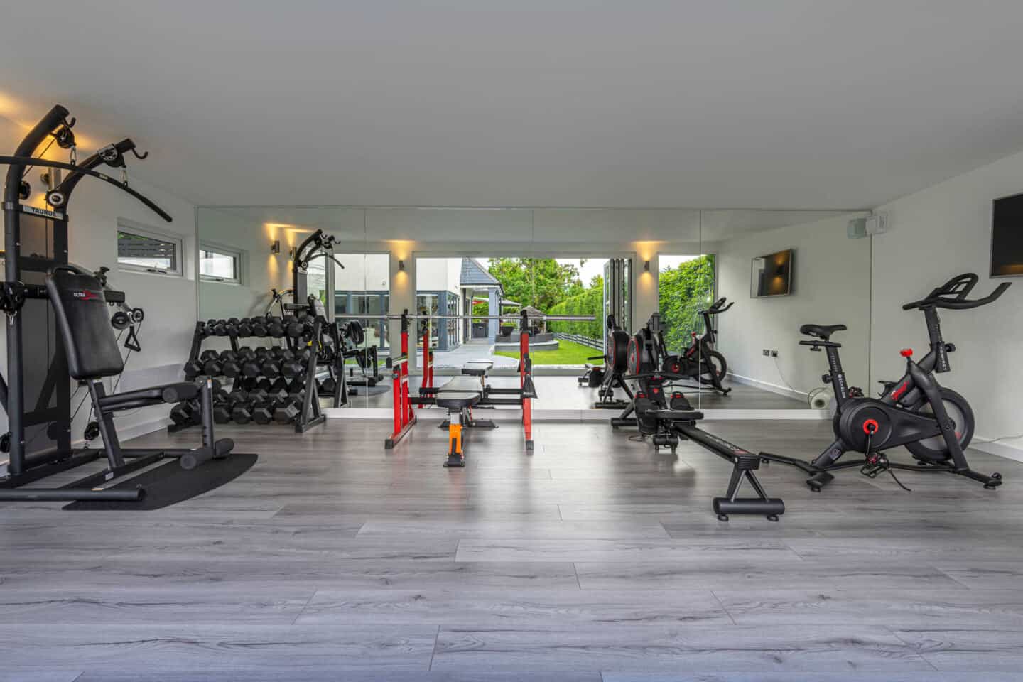 Home gym full of workout equipment and machinery with views to the garden