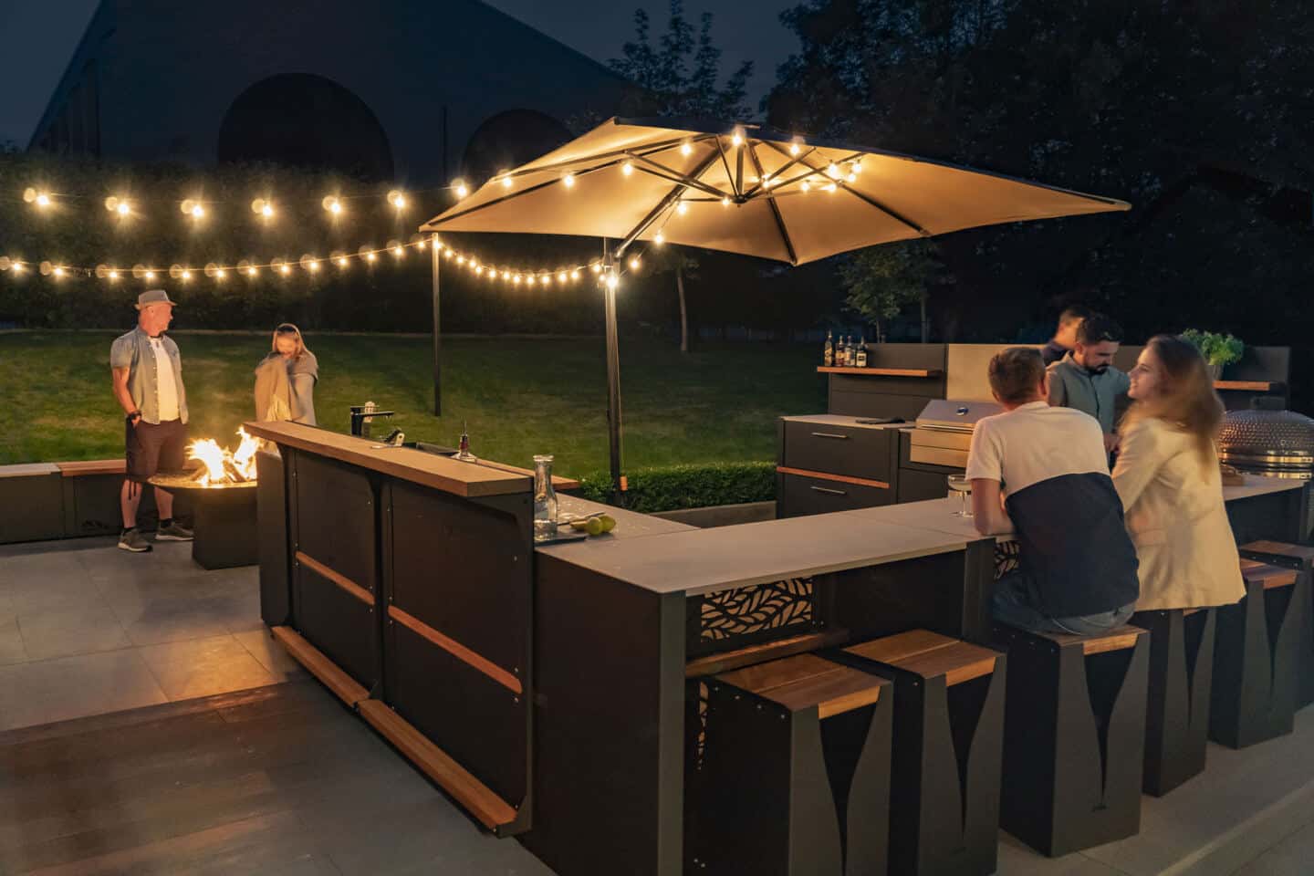 People sitting round an outdoor bar at night in a large garden