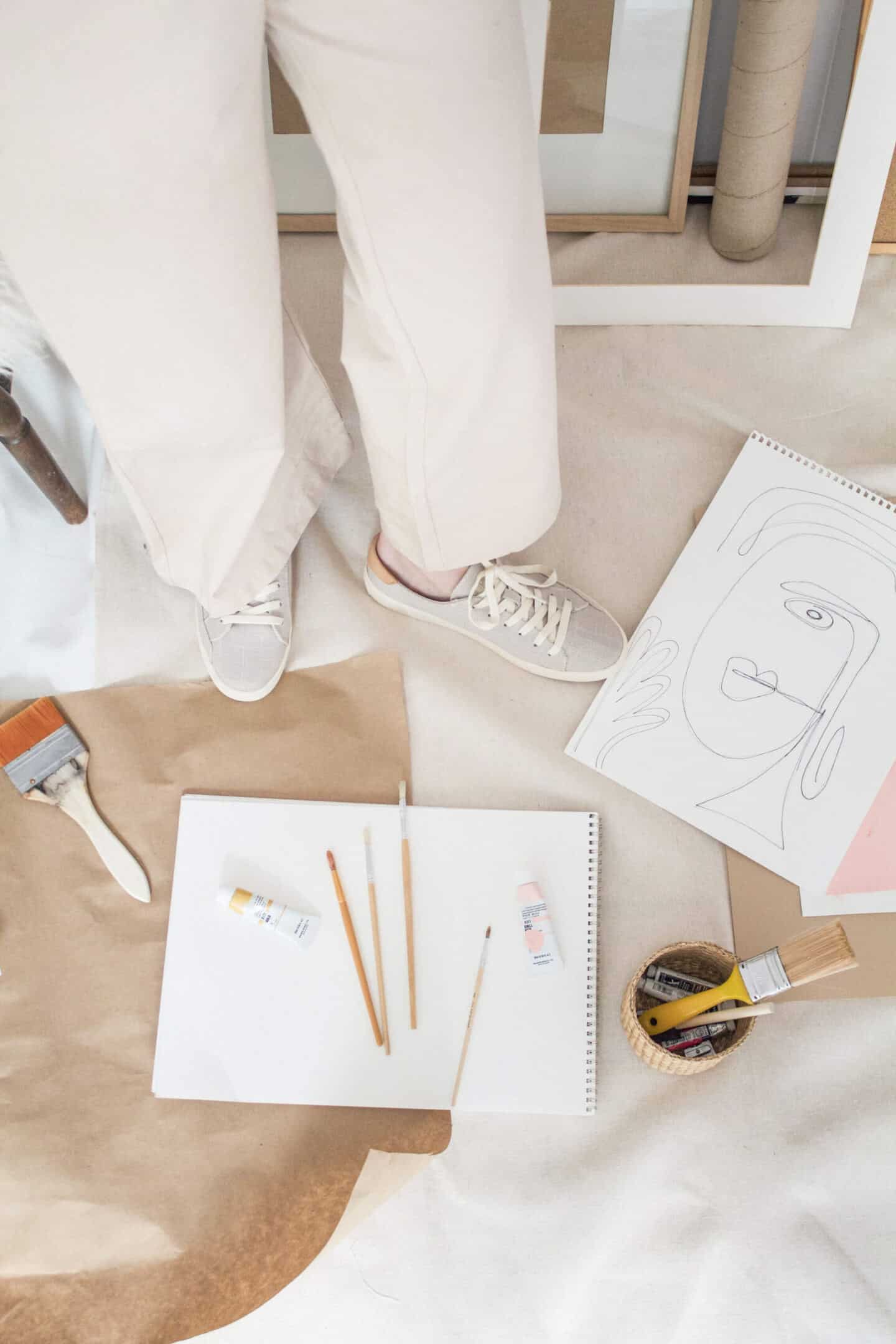 Paint brushes and artist's drawing pads on the floor of a studio in a spare room