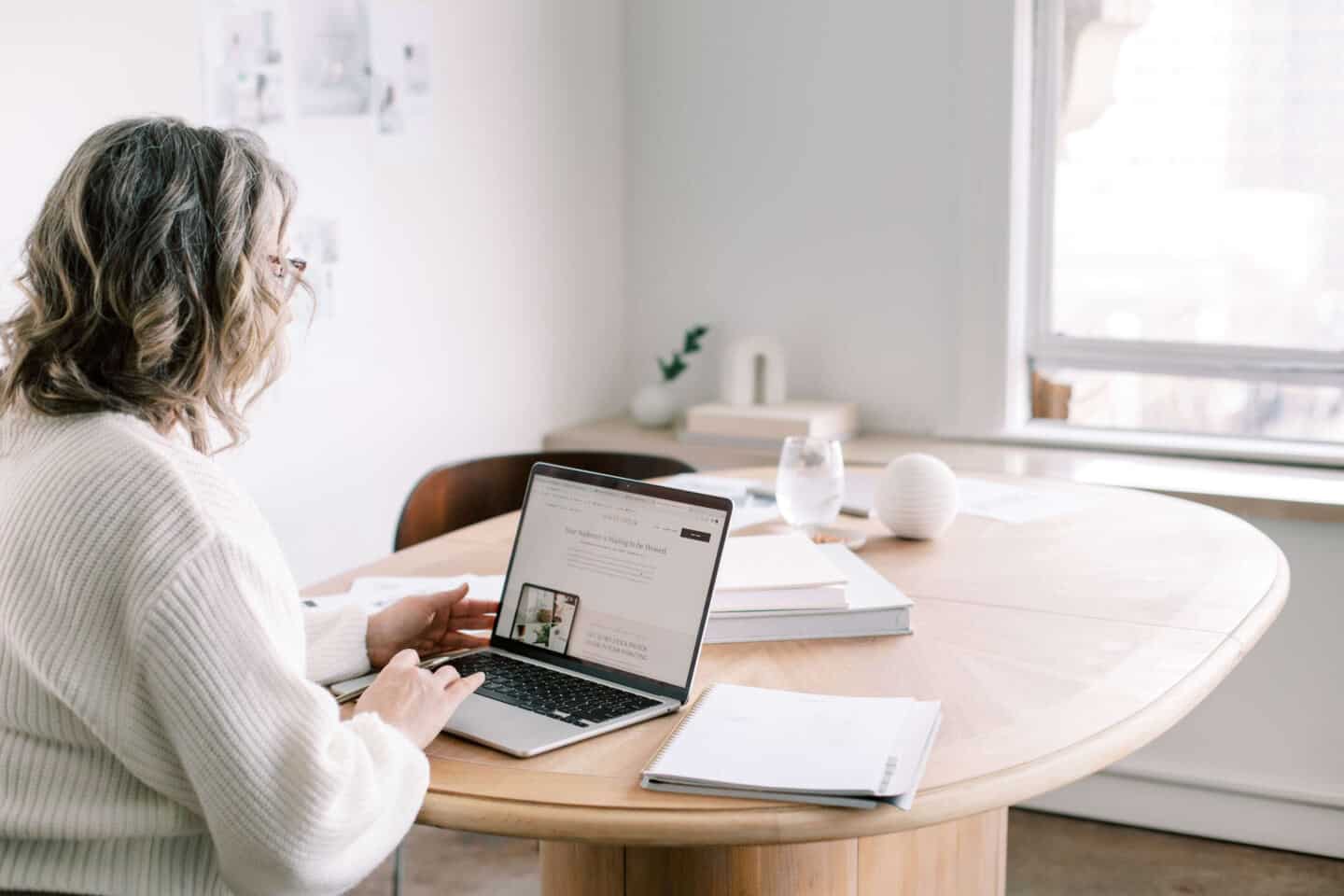 A middle aged woman sat at a desk on a laptop