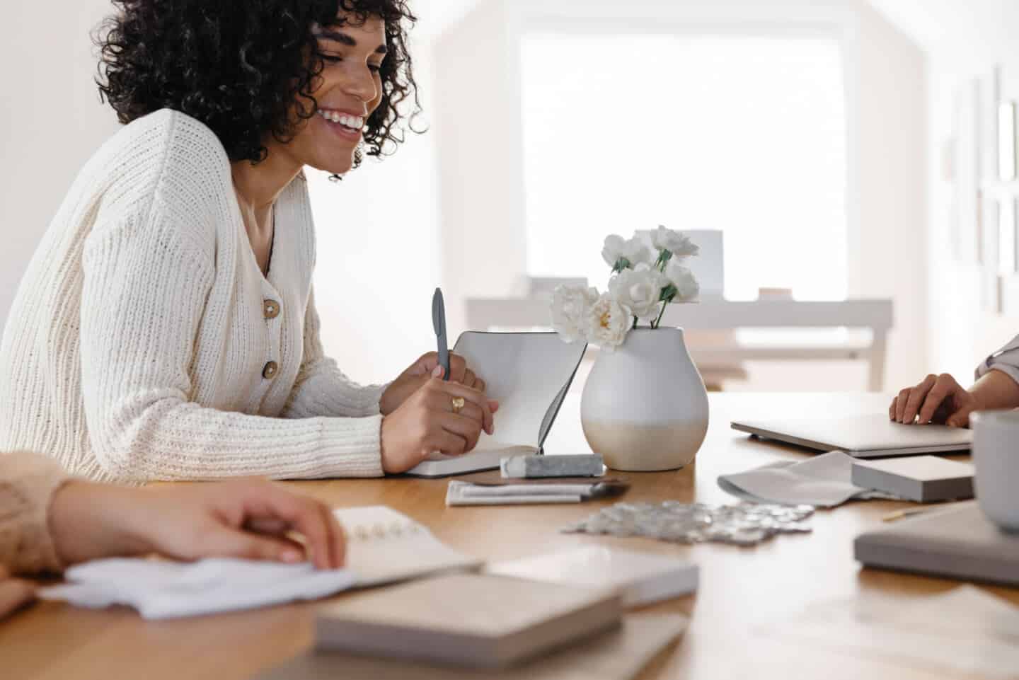 3 women sit around a table planning an interior design project