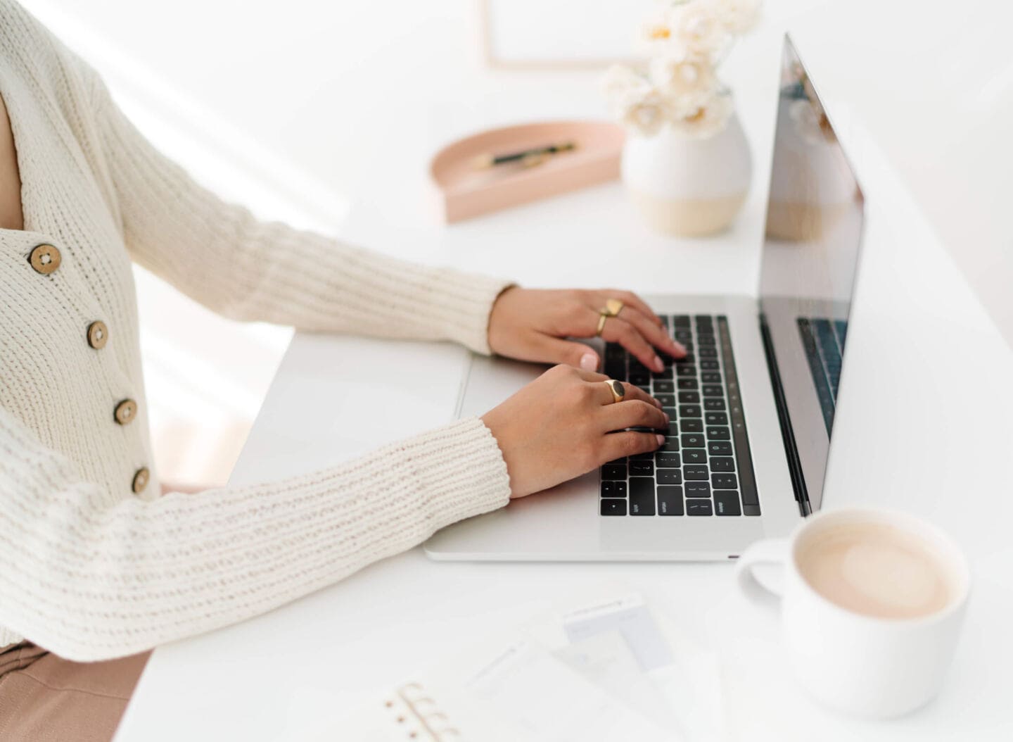 A woman sits at a desk and types on a laptop