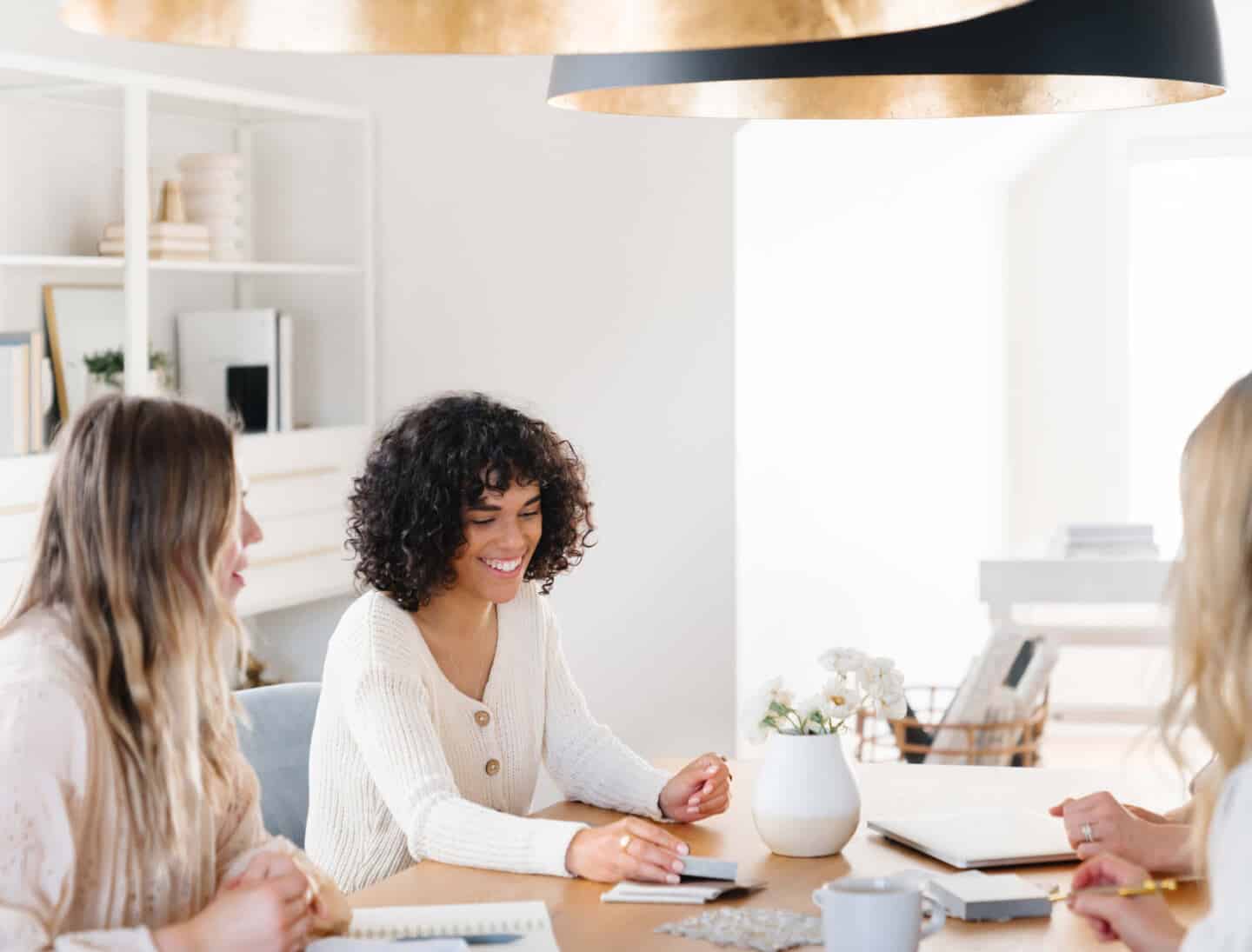 3 women sit around a table planning an interior design project