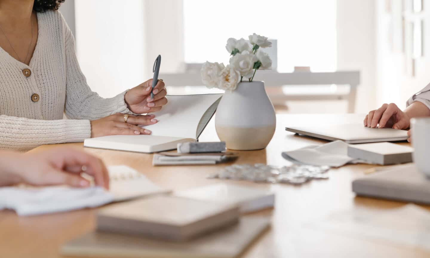 3 women sit around a table planning an interior design project