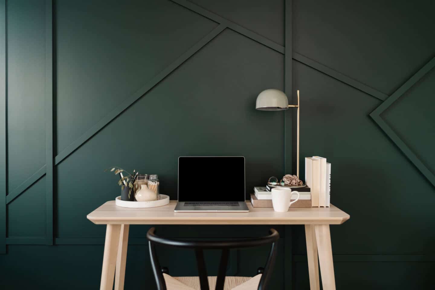 A white oak desk against a dark green wall