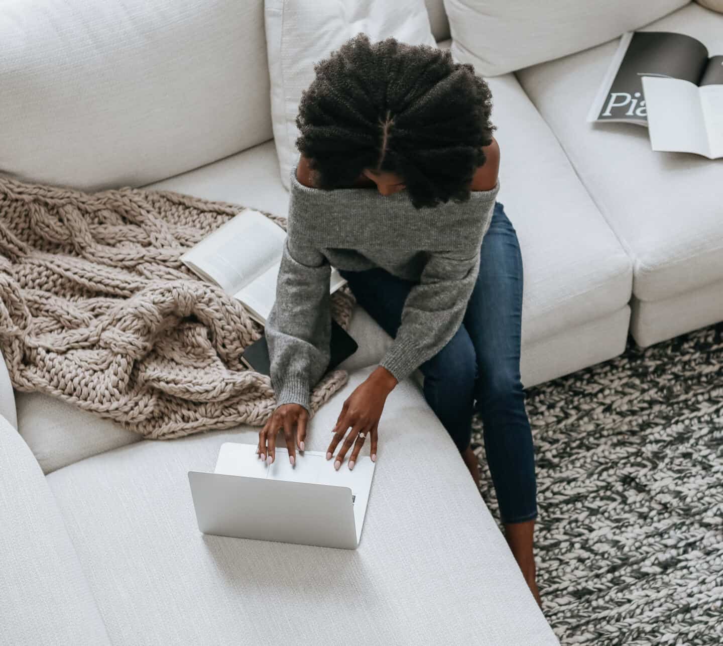 A young woman sat on a sofa using a laptop