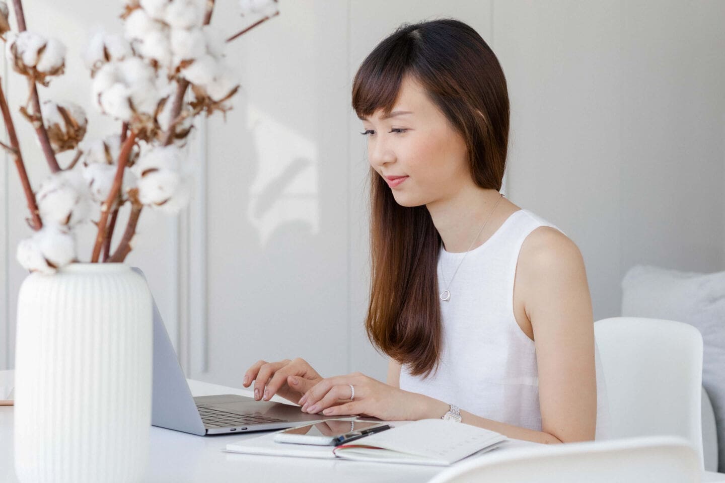 A young Asian woman sat at a desk on a laptop