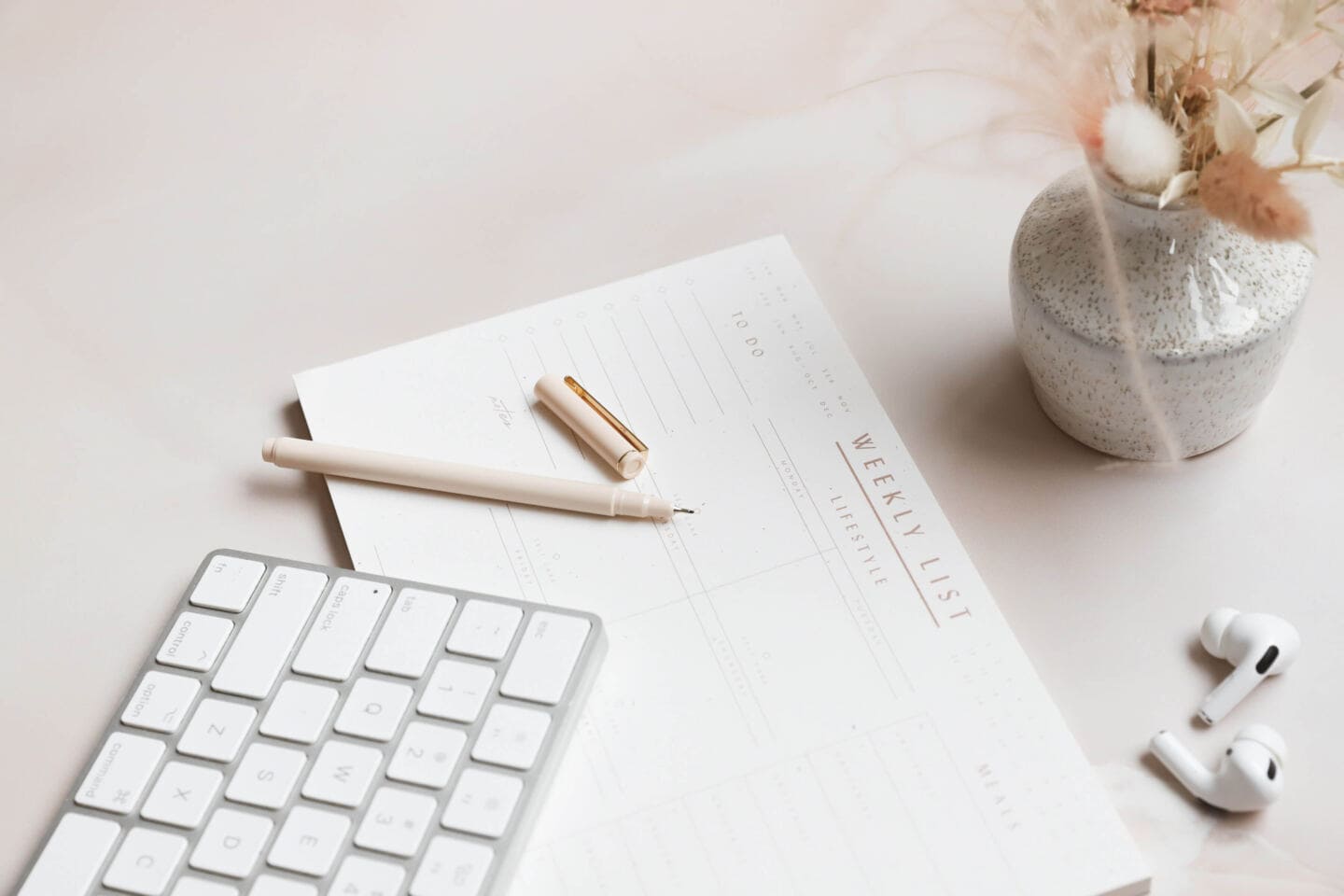 A weekly paper planner and a wireless keyboard on a desk