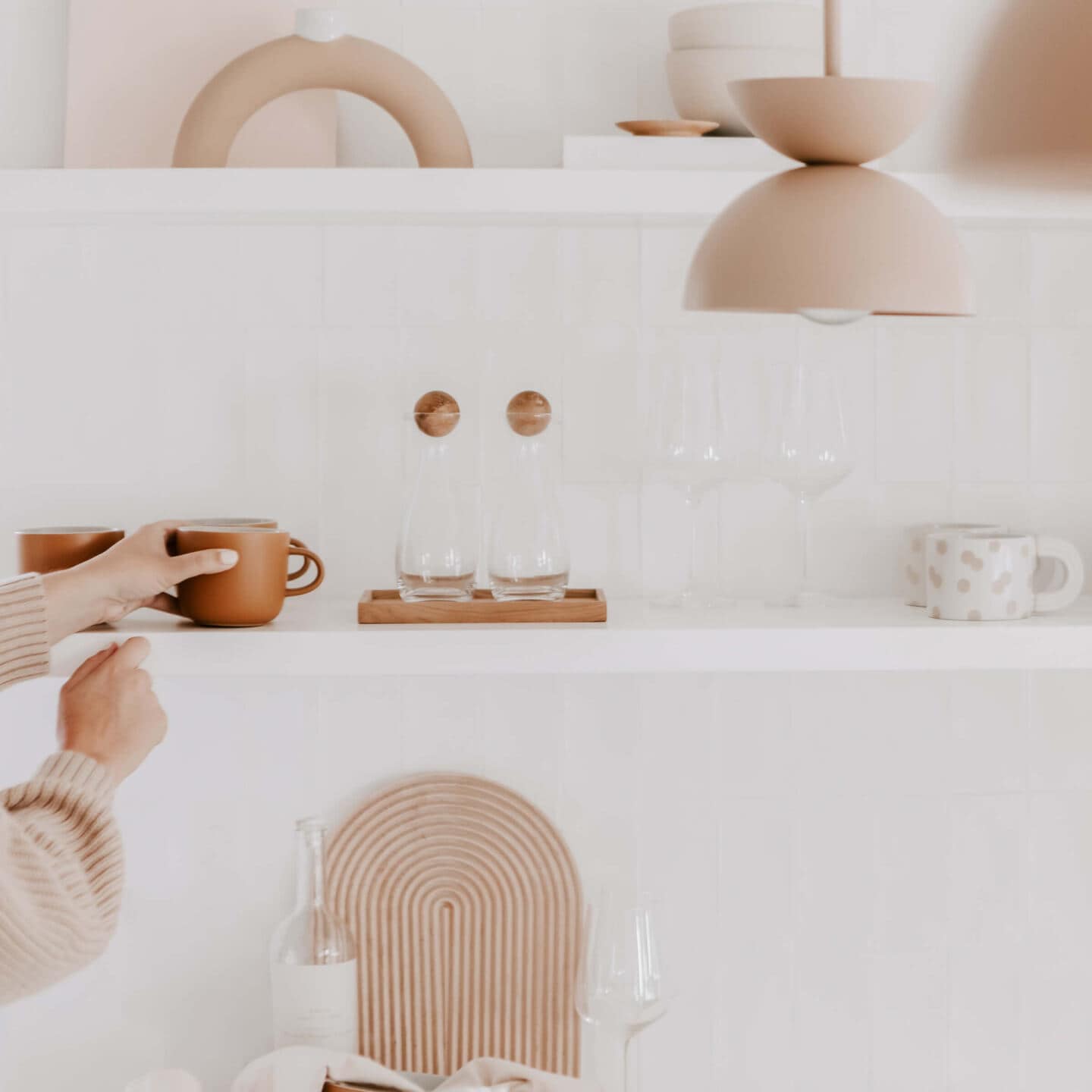 A woman adds items to a kitchen shelf