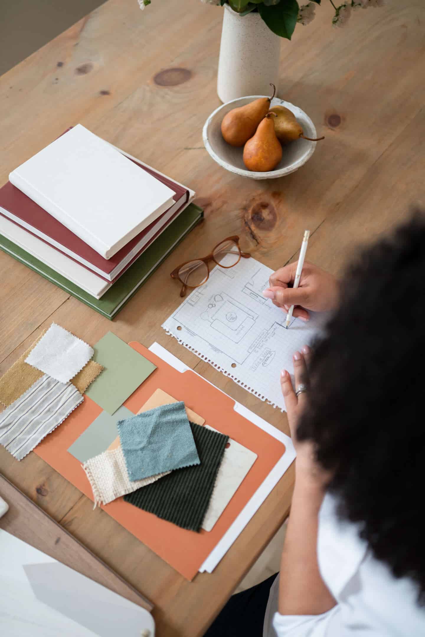 A young woman who runs an interior design business drawing sketches of a room plan on squared paper