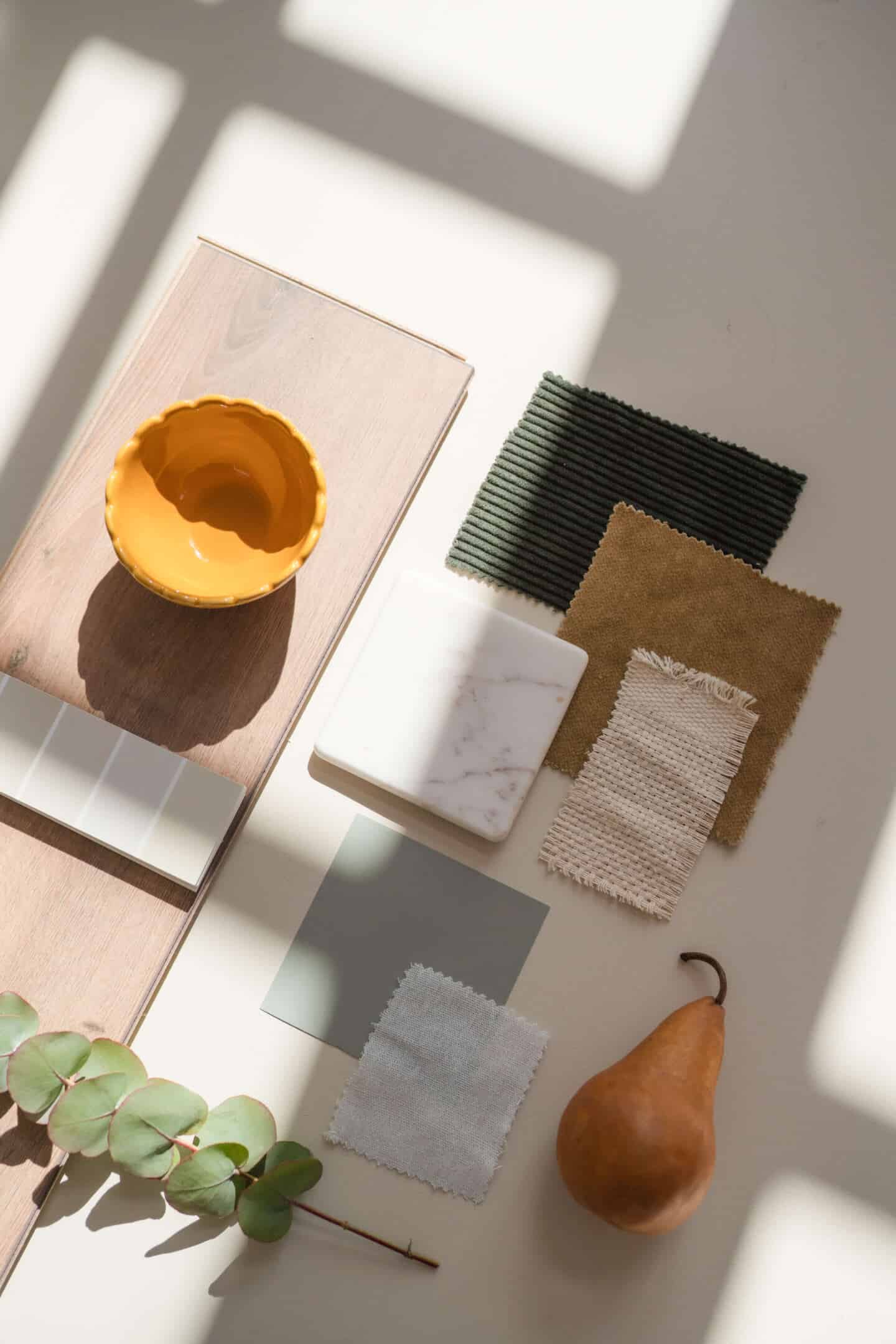 An interior design moodboard featuring fabric samples, paint chits, a wooden floorboard and a tile sample