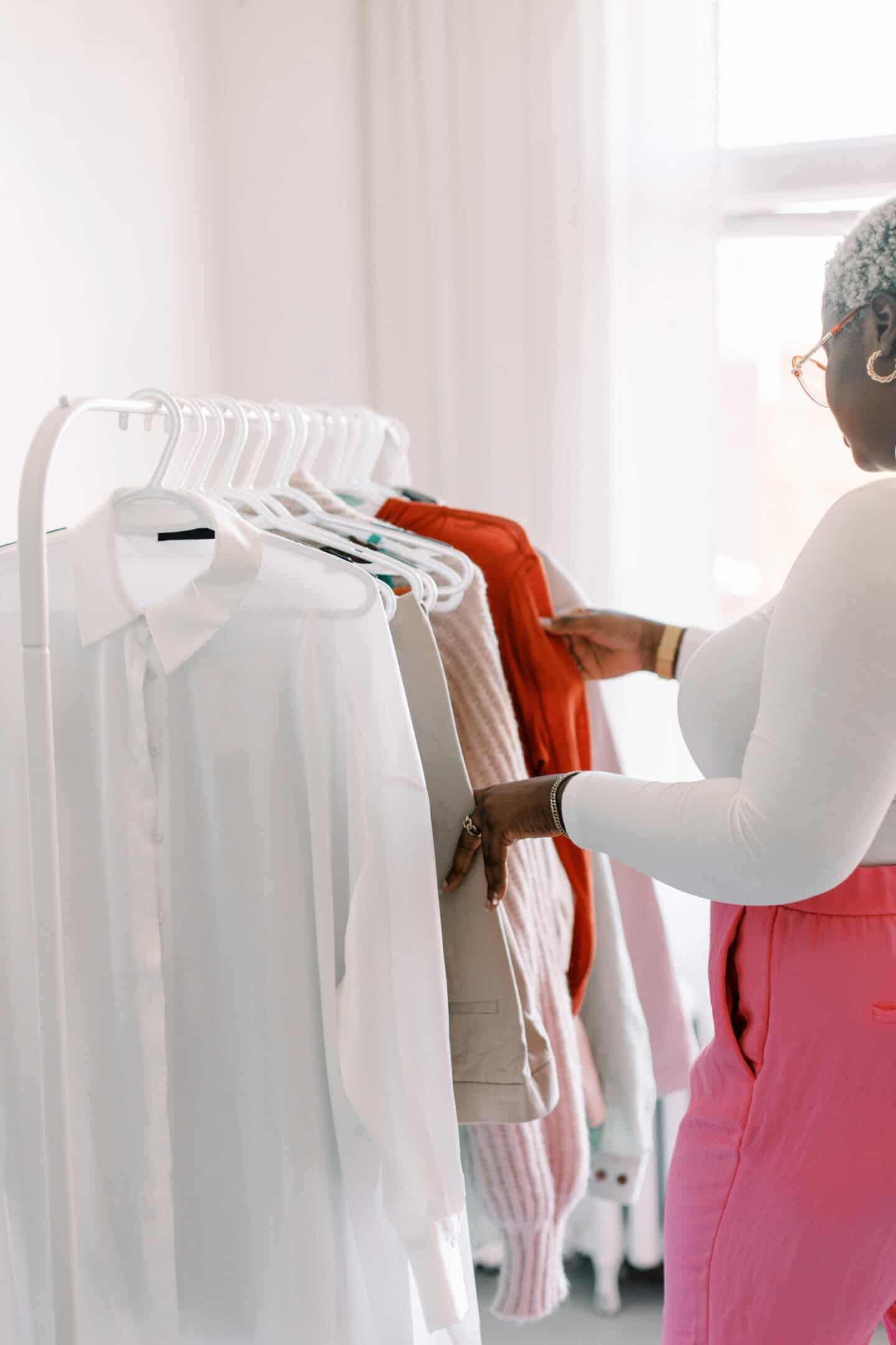 A young black woman looks through a rail of clothes