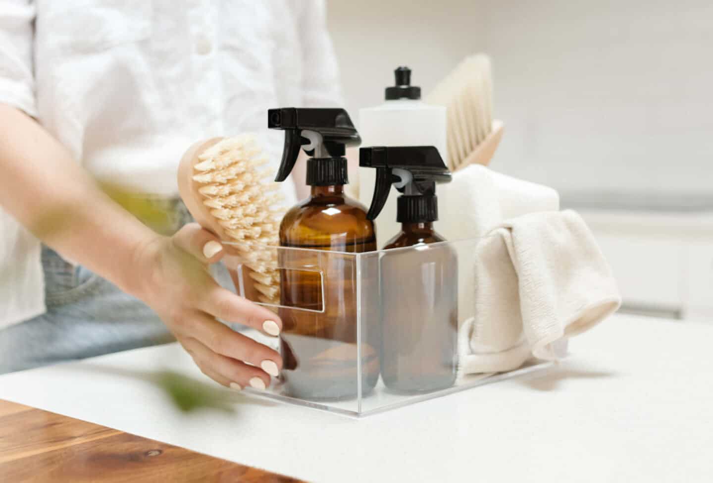 A woman holding a clear box full of cleaning products