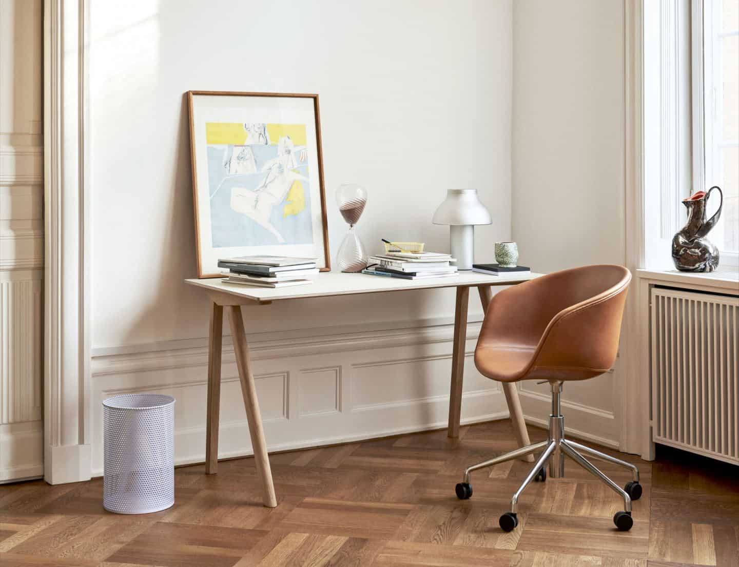 A small space-saving desk in the corner of the room next to a window