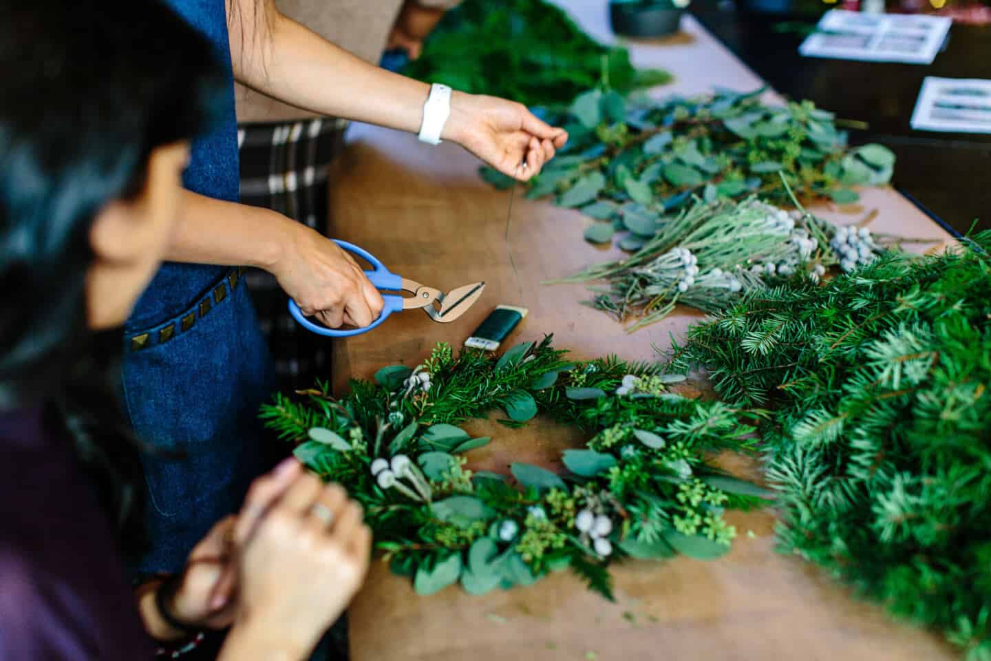 Two women making Christmas wreaths or garlands