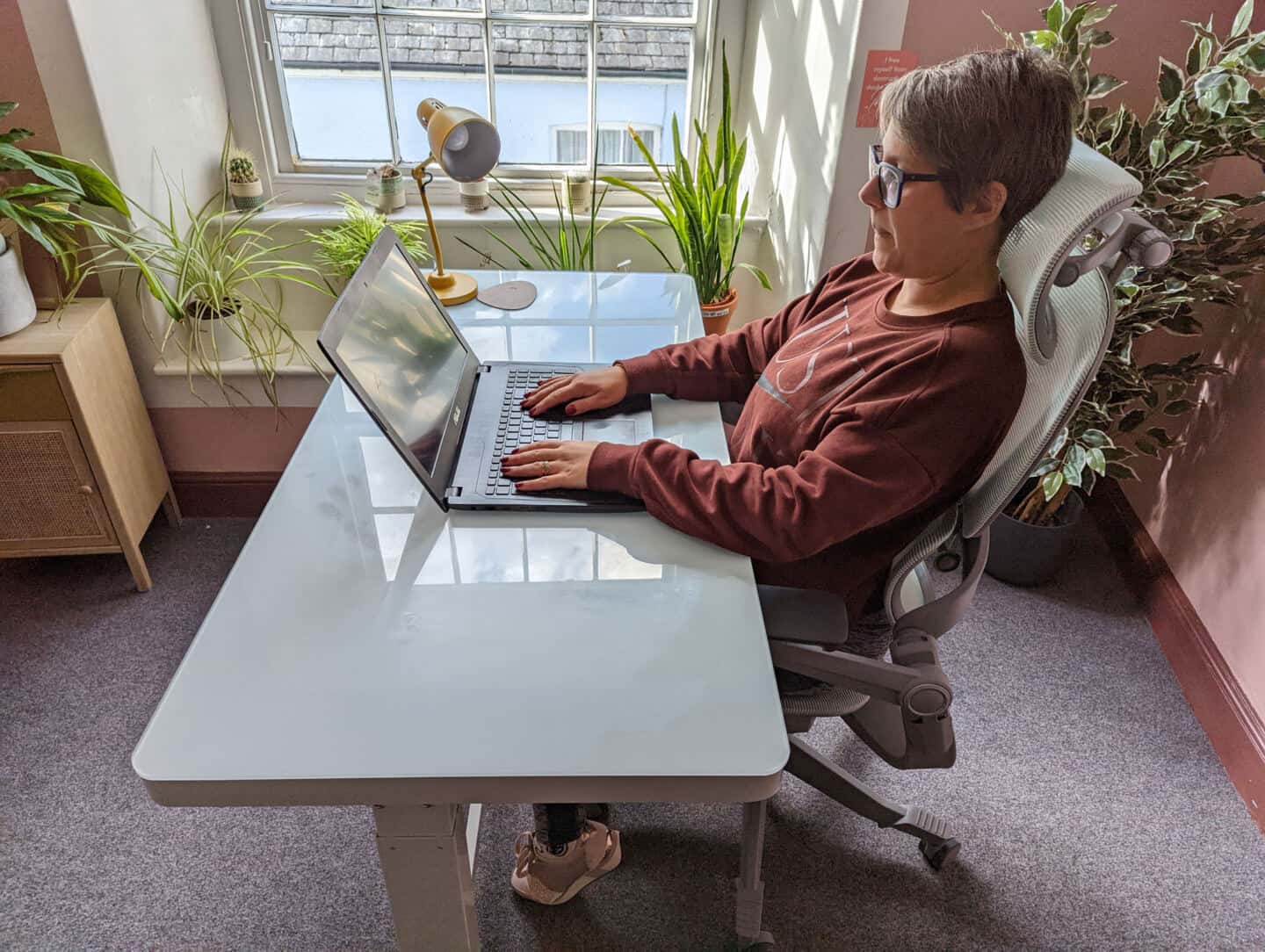 A woman sat at a desk working on a laptop