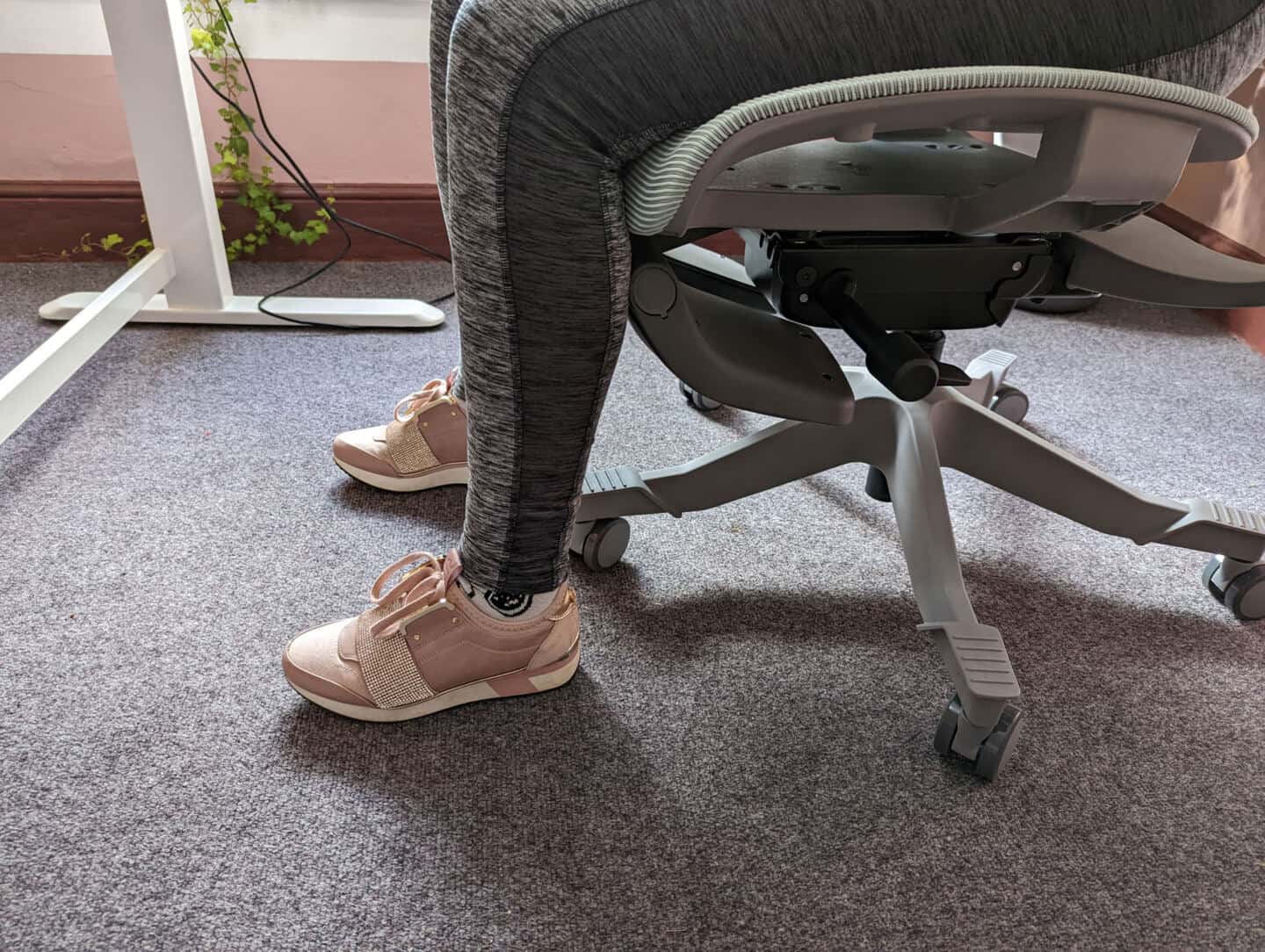 A close up of the legs of a woman sat in an ergonomic office chair