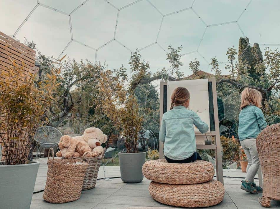 two young children painting and playing inside a garden dome