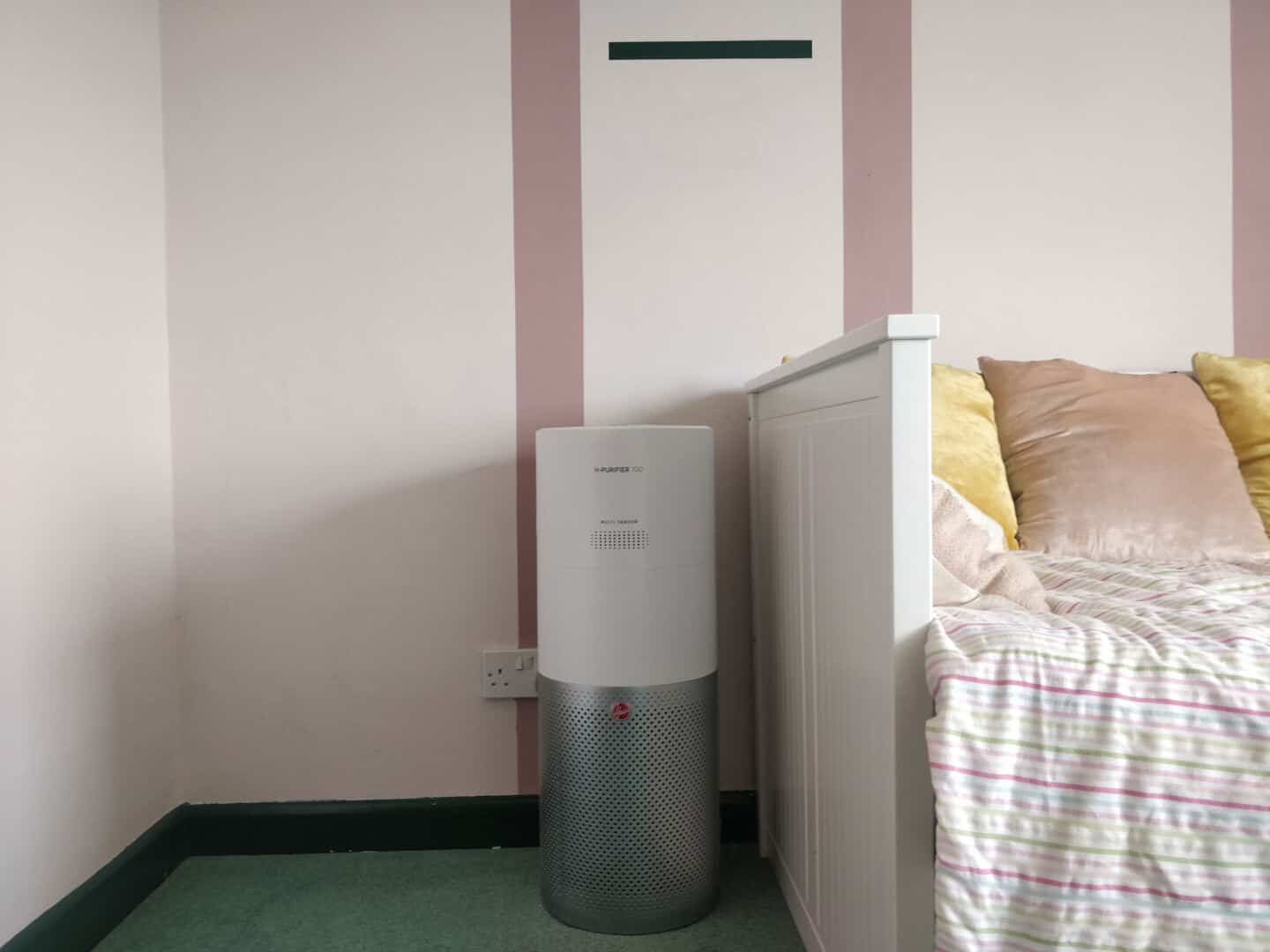 The Hoover Air Purifier 700 stands next to a day bed in a bedroom.