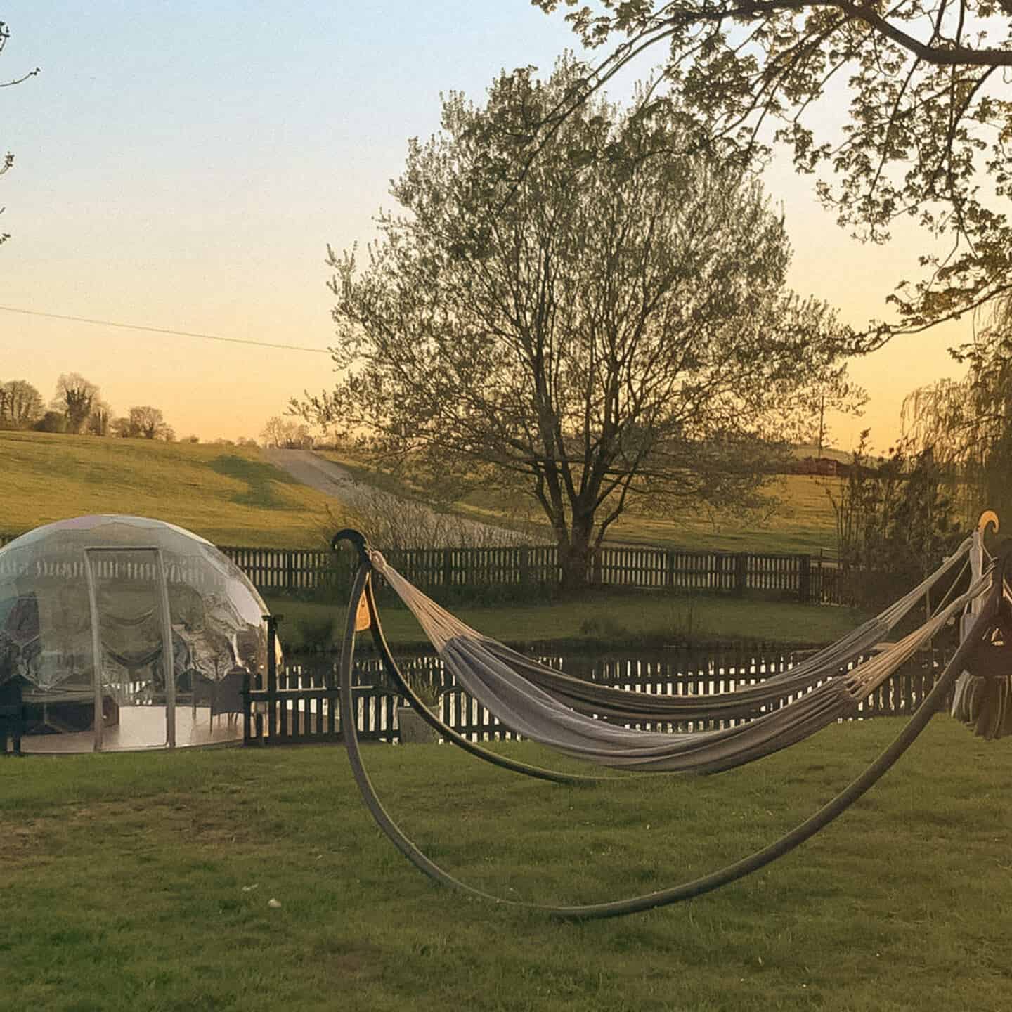 A garden dome sits next to a small lake surrounded by hills