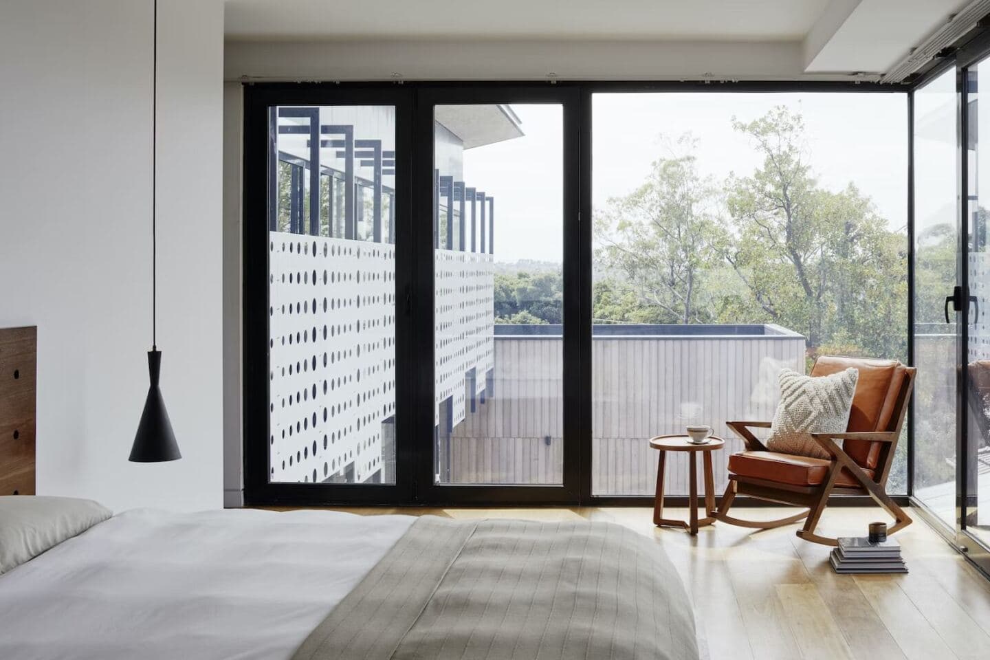 A bedroom with dual aspect floor to ceiling windows