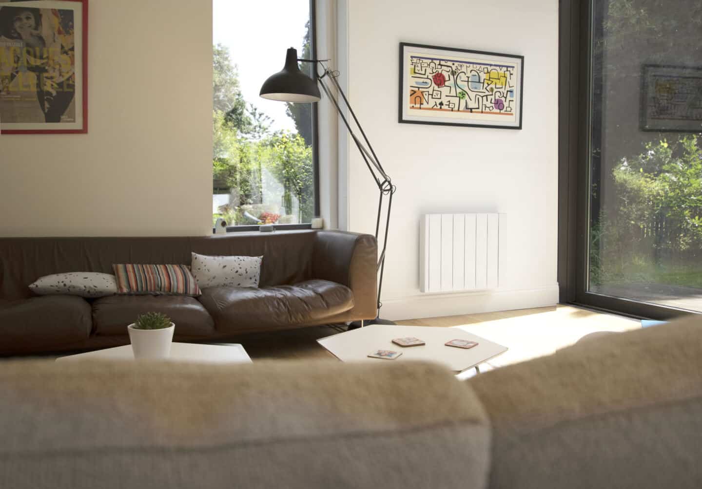 The Ecostrad iQ Ceramic smart electric radiator on a white wall in a modern living room