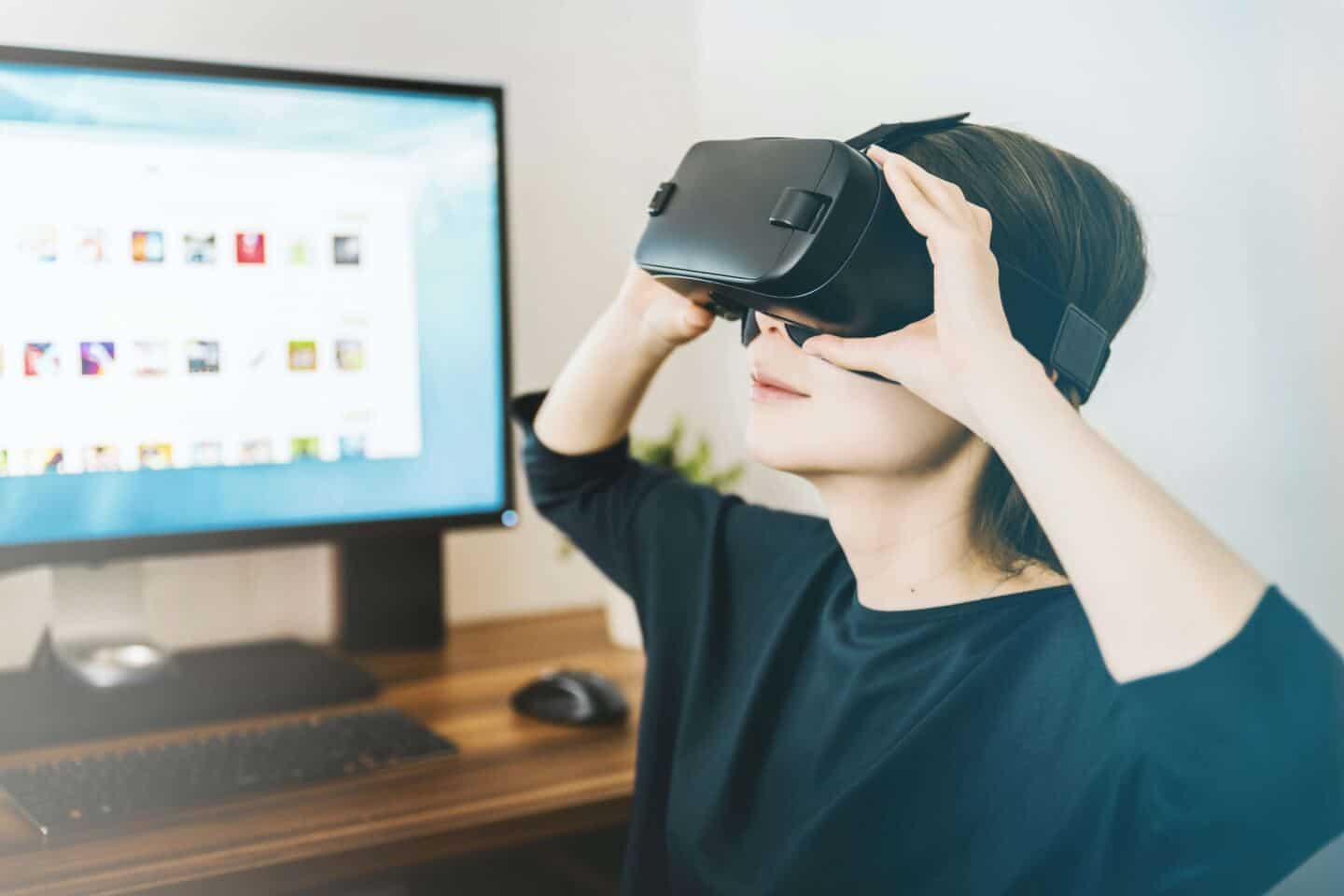 A woman sat at a computer using a VR headset