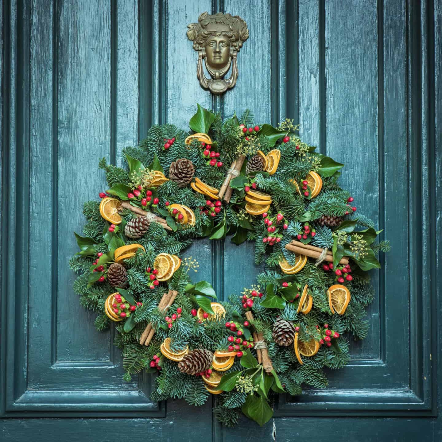 Christmas wreath hanging on a teal wooden front door