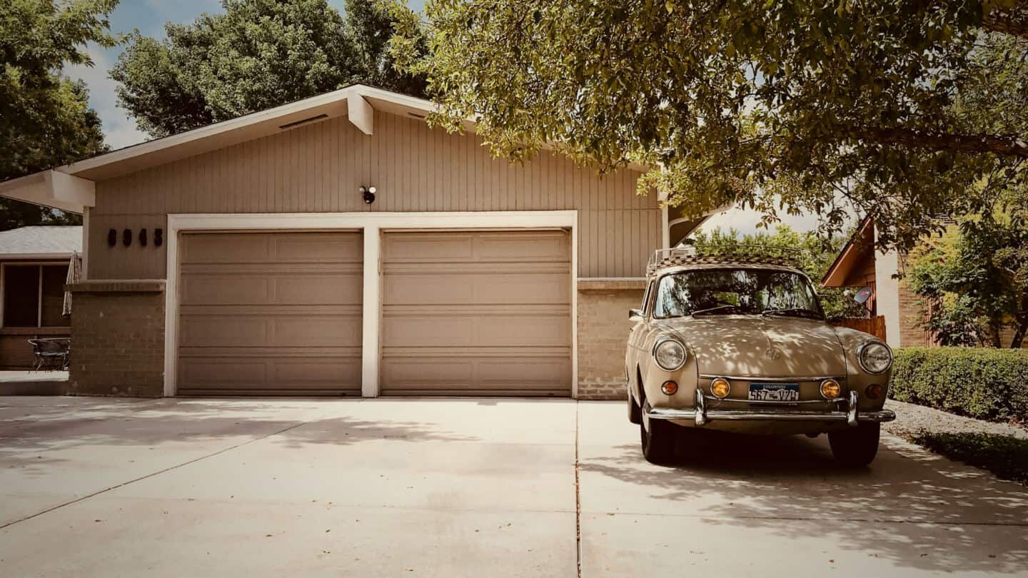 A car parked on a driveway outside a double garage