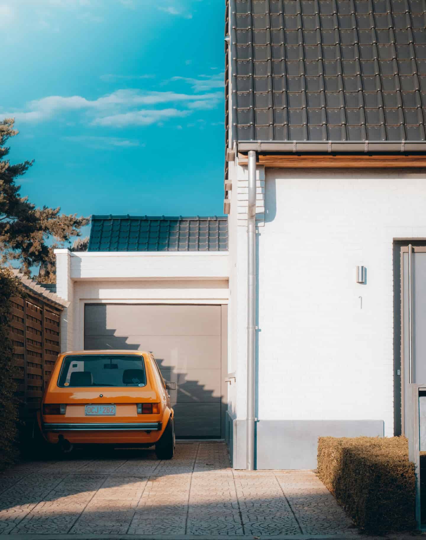 A car is packed on the driveway outside the garage which attached to the house