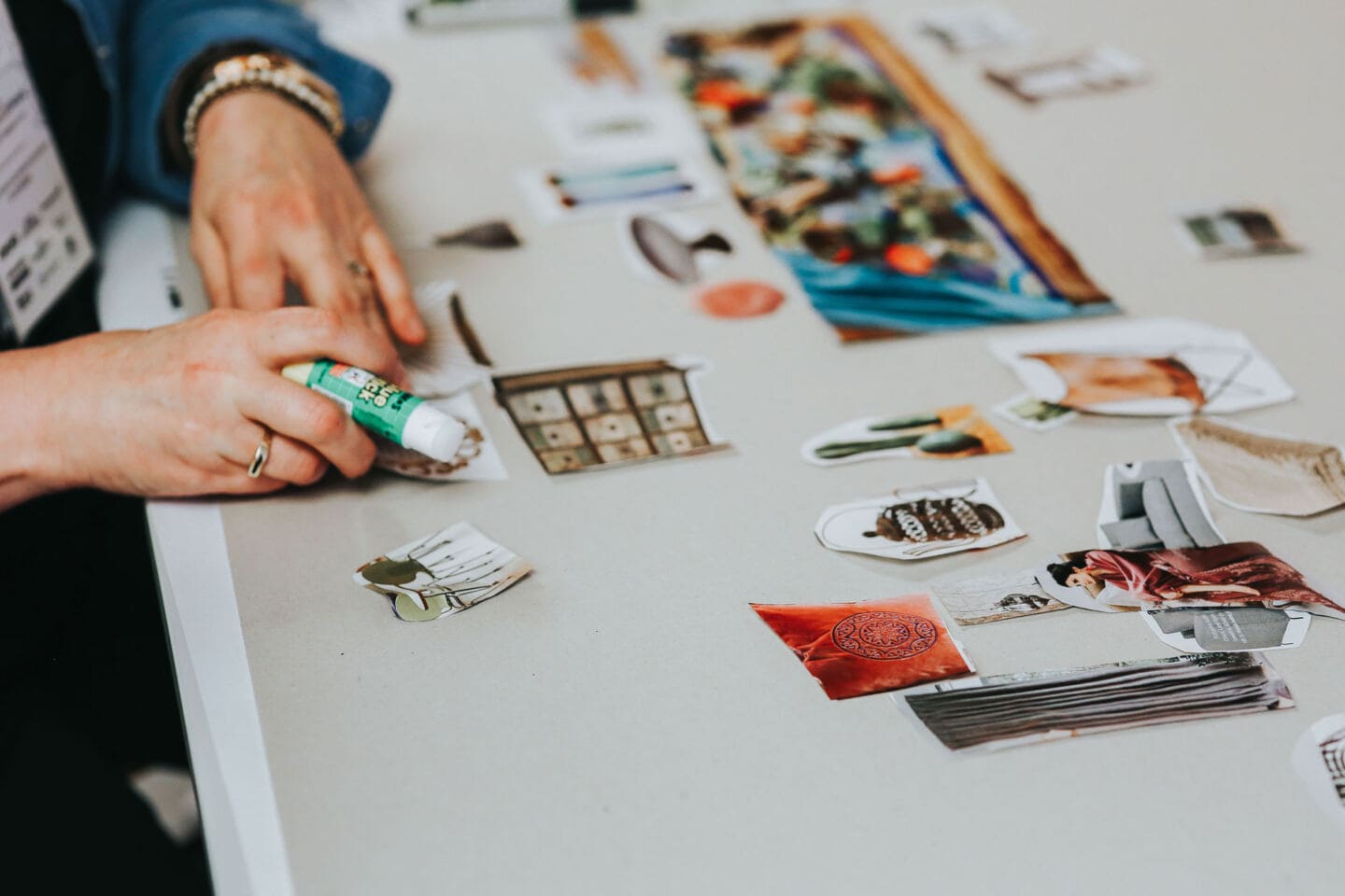 A woman creates a mood board featuring lots of home interior pictures cut out of magazines and catalogues.