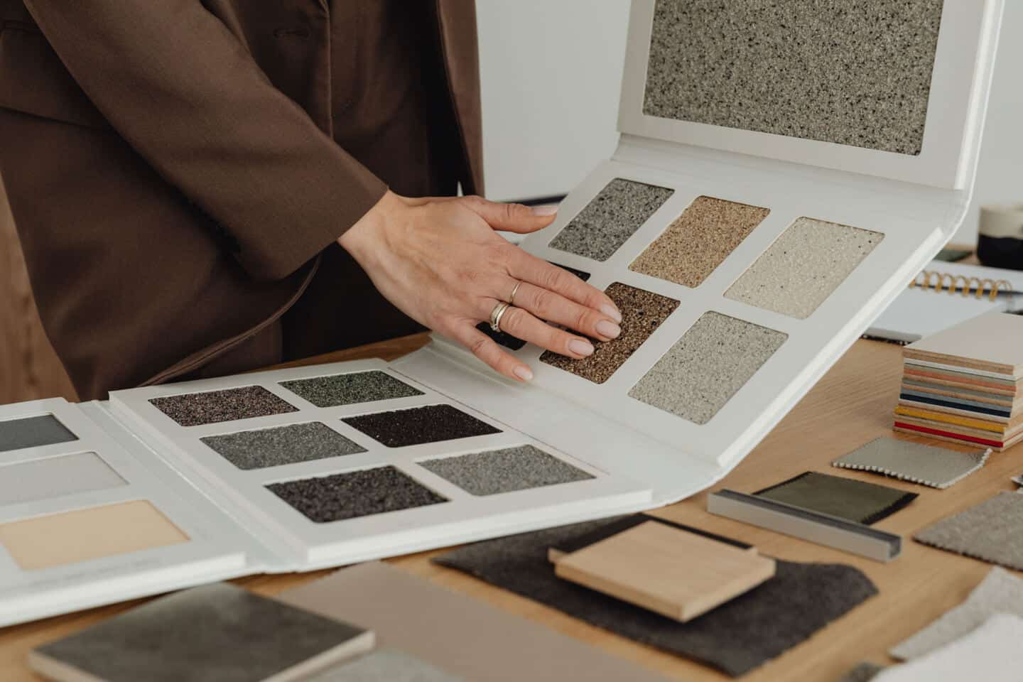 A woman holds a book containing material samples for an interior design project