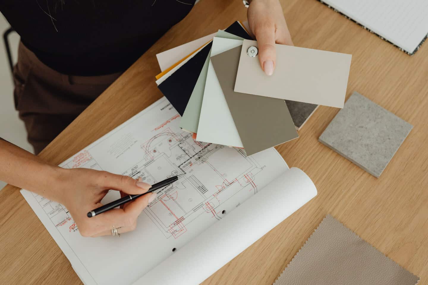 An interior designer looks at colour swatches on her desk next to a floor plan