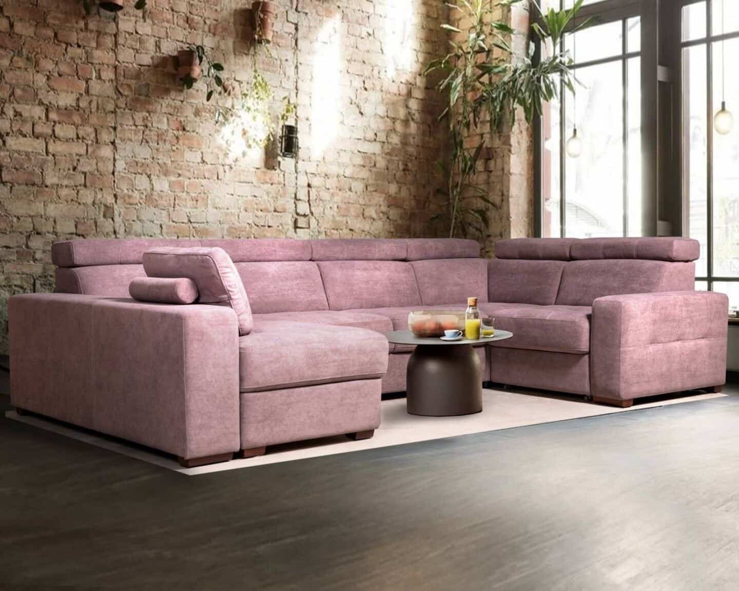 How to choose the perfect sofa for your lifestyle.  Modular pink sofa in anfront of an exposed brick wall with plants hung on the wall and a large window to the right.